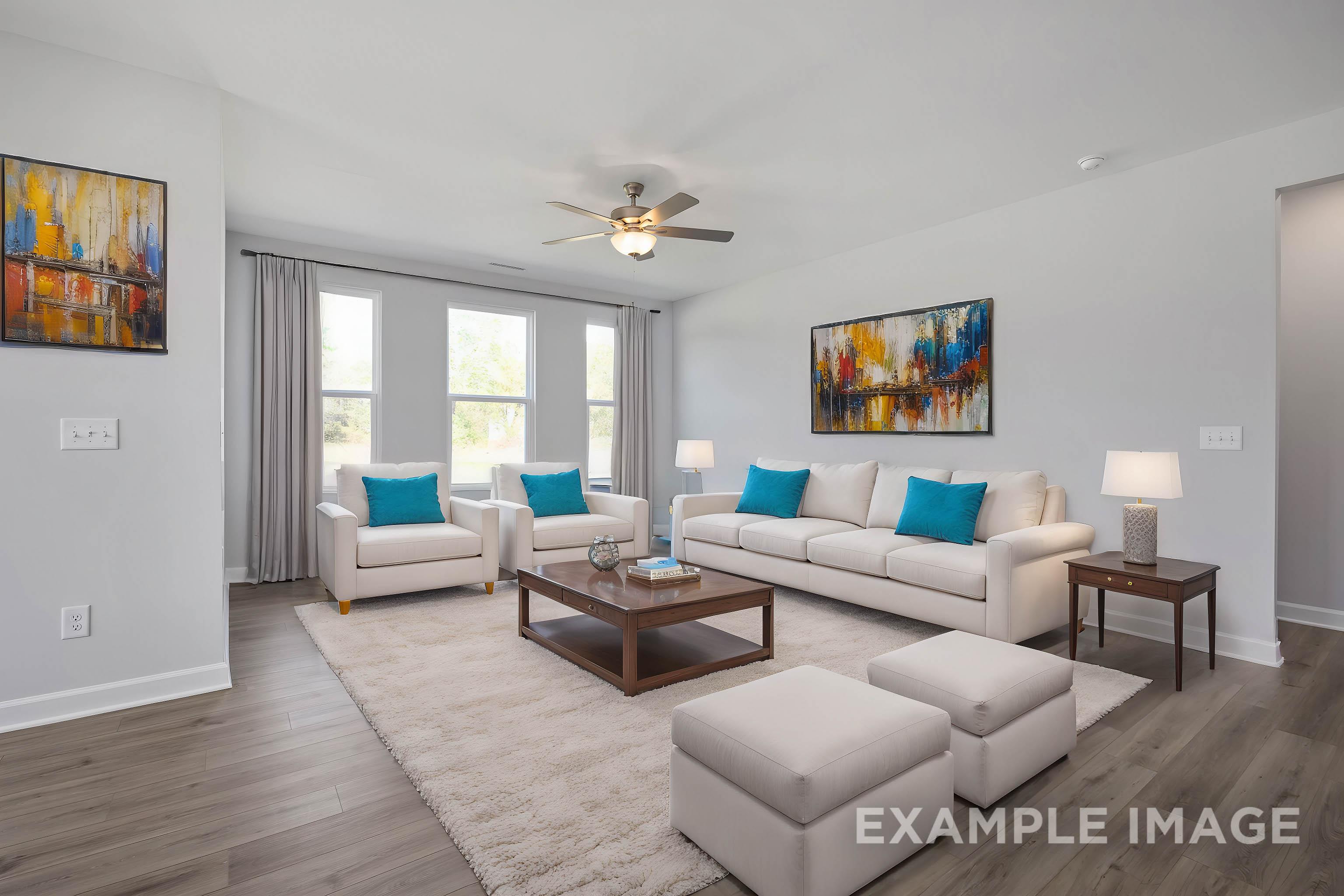 Spacious living room in The Ash Davidson Homes design with beige sectional sofa, accent chairs, coffee table, ceiling fan, and abstract wall art