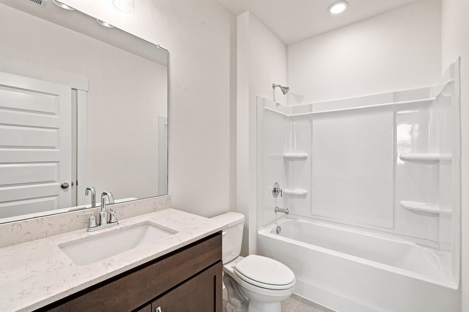 Bright bathroom with quartz vanity, wood cabinet, and tub shower combo in Davidson Homes The Willow C, Gallatin, TN