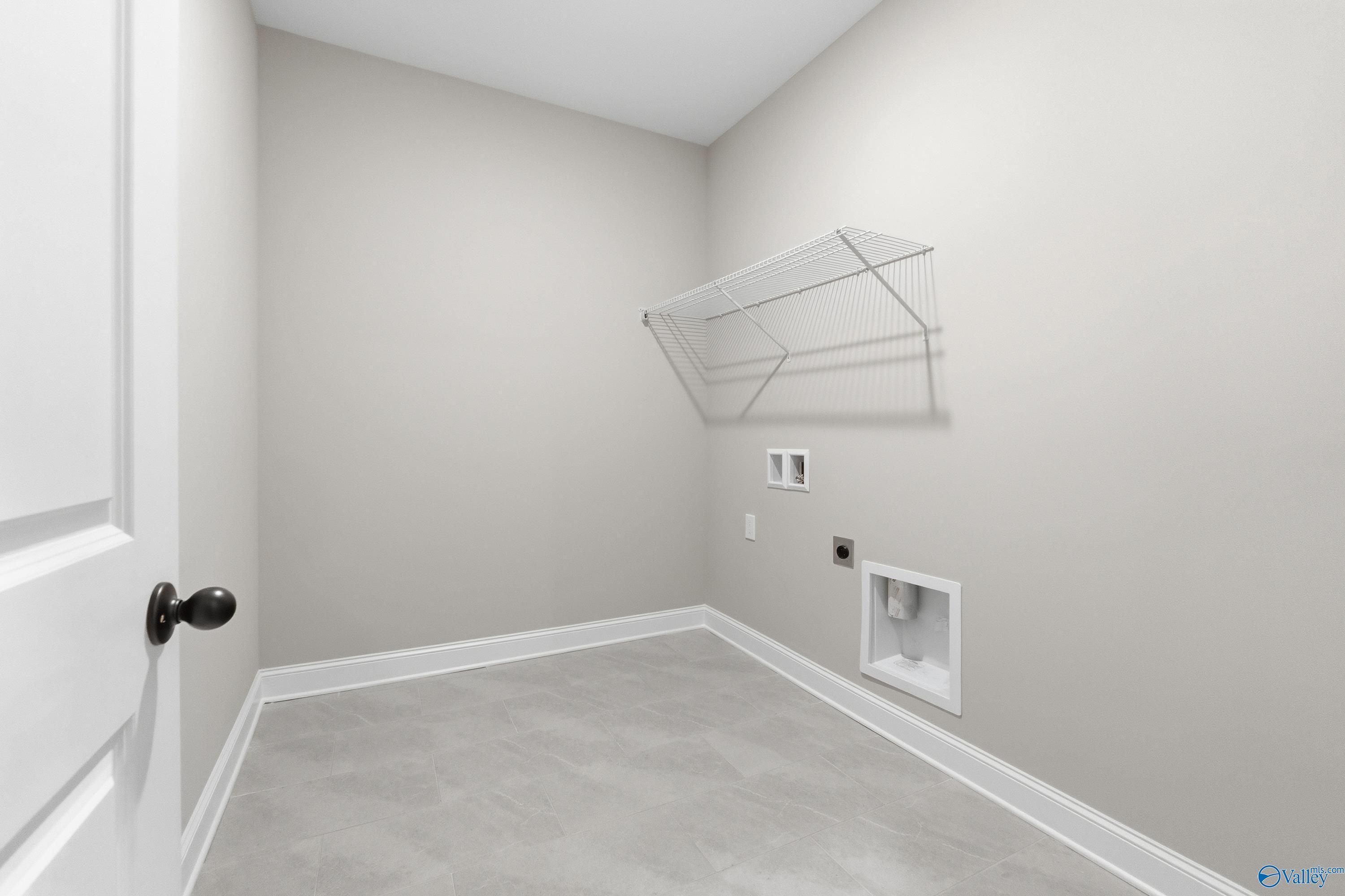 Spacious laundry room with open wire shelving, washer dryer hookups, and utility sink in Davidson Homes The Finleigh, Meridianville, Alabama