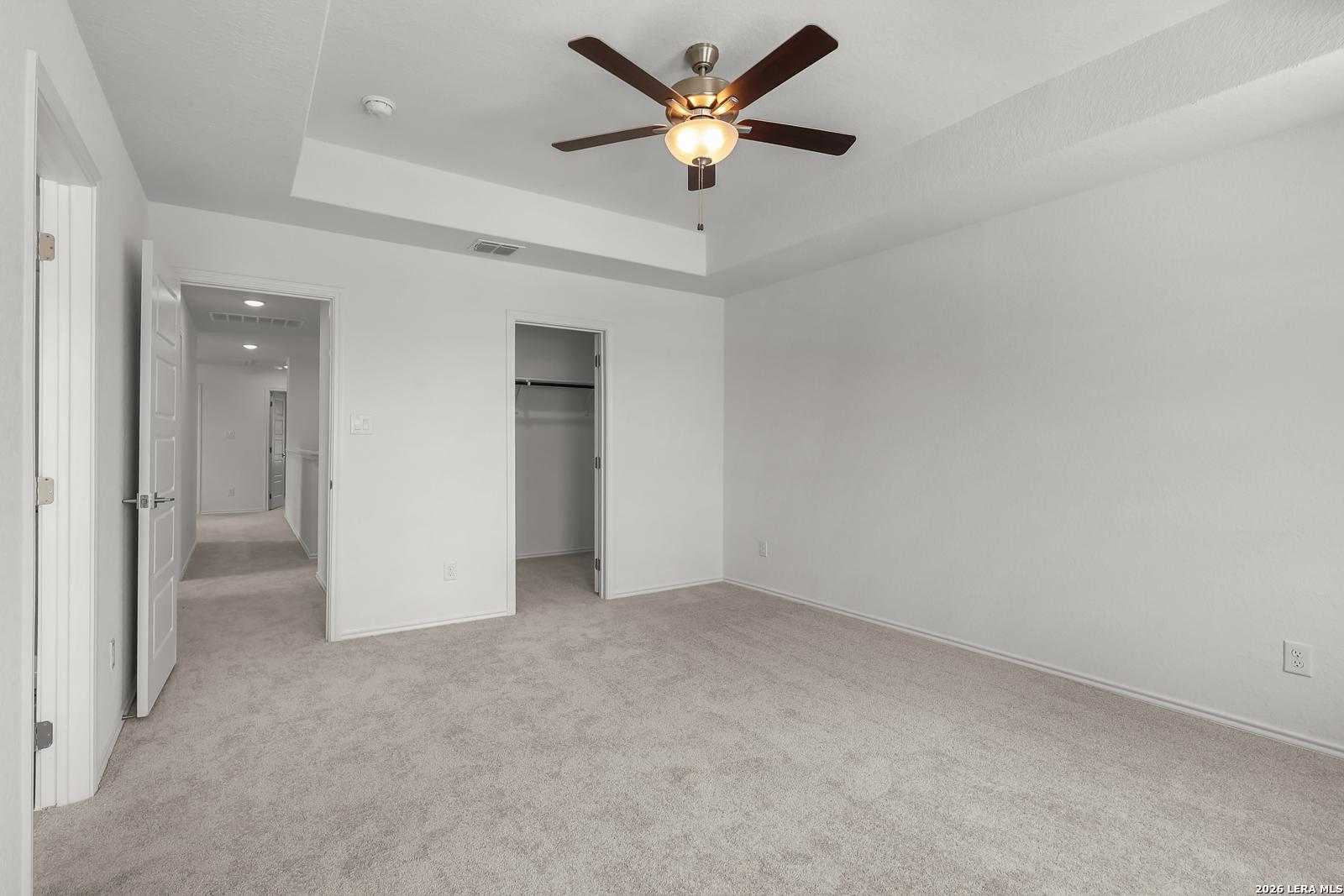 Spacious bedroom with tray ceiling and ceiling fan in The Gillian C floor plan at Meadows at Oak Creek, San Antonio, Texas.