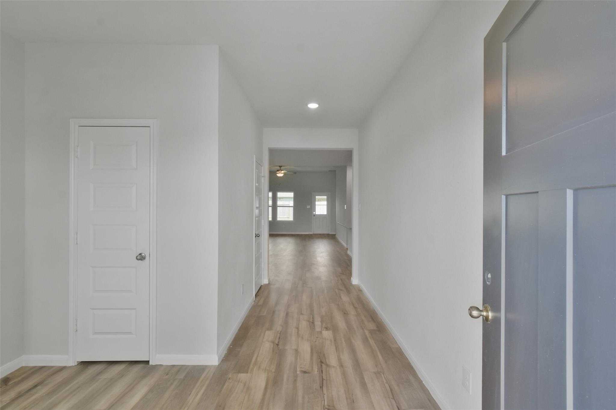 Bright hallway with luxury vinyl plank flooring, white walls, and ceiling fan in Davidson Homes Tierra A, Dayton Texas