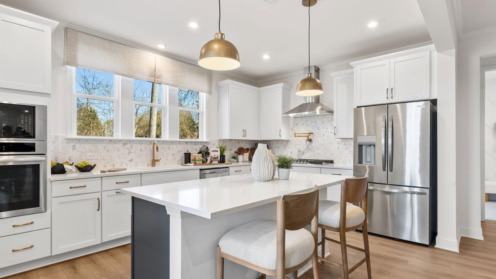 Open-concept kitchen dining living area in Fern Hollow Buford GA with white quartz island hardwood floors pendant lights