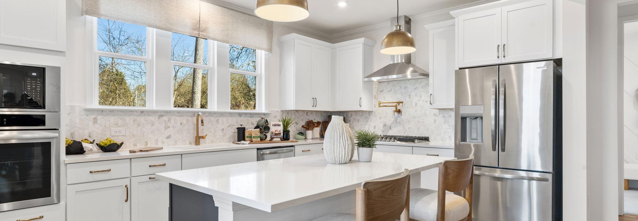 Open-concept kitchen dining living area in Fern Hollow Buford GA with white quartz island hardwood floors pendant lights