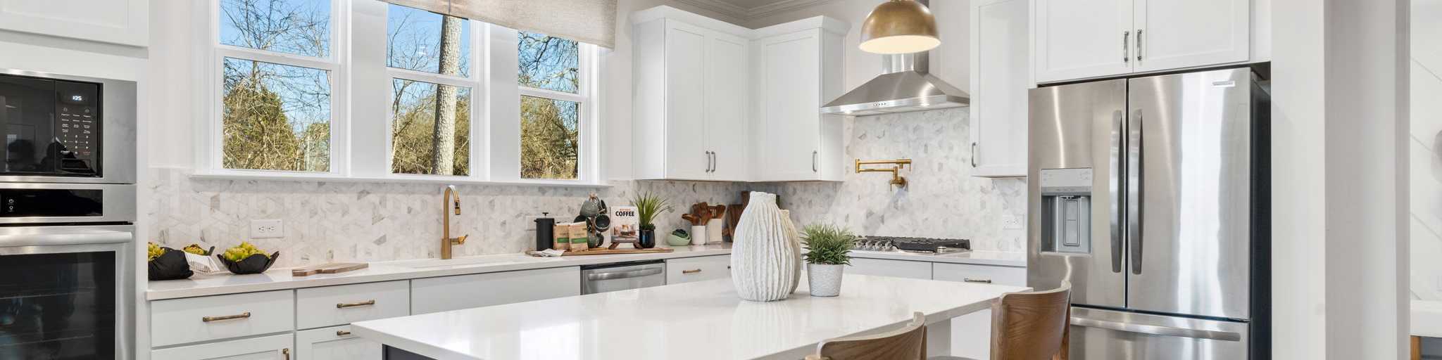 Open-concept kitchen dining living area in Fern Hollow Buford GA with white quartz island hardwood floors pendant lights