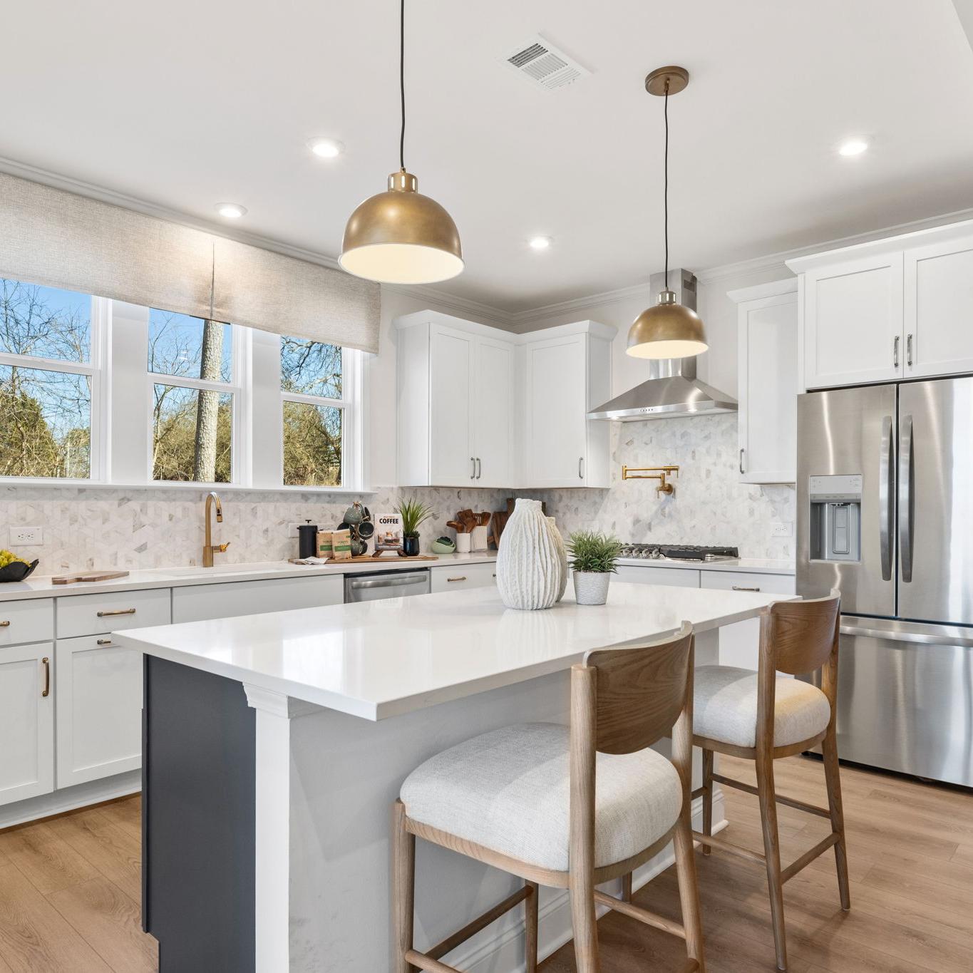Open-concept kitchen dining living area in Fern Hollow Buford GA with white quartz island hardwood floors pendant lights