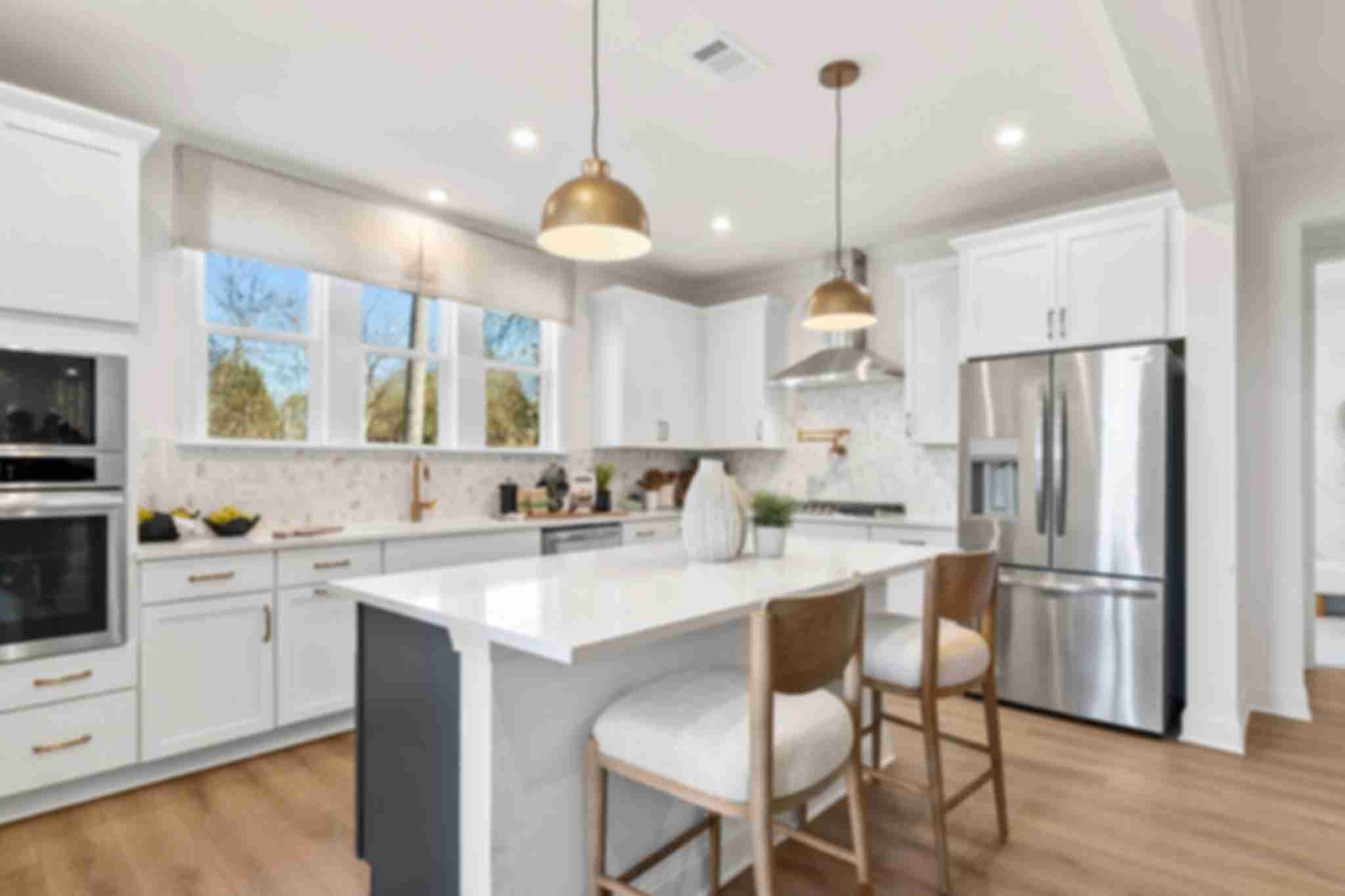Open-concept kitchen dining living area in Fern Hollow Buford GA with white quartz island hardwood floors pendant lights