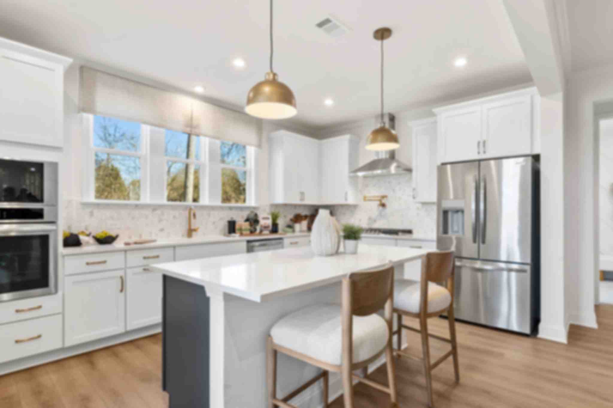 Open-concept kitchen dining living area in Fern Hollow Buford GA with white quartz island hardwood floors pendant lights