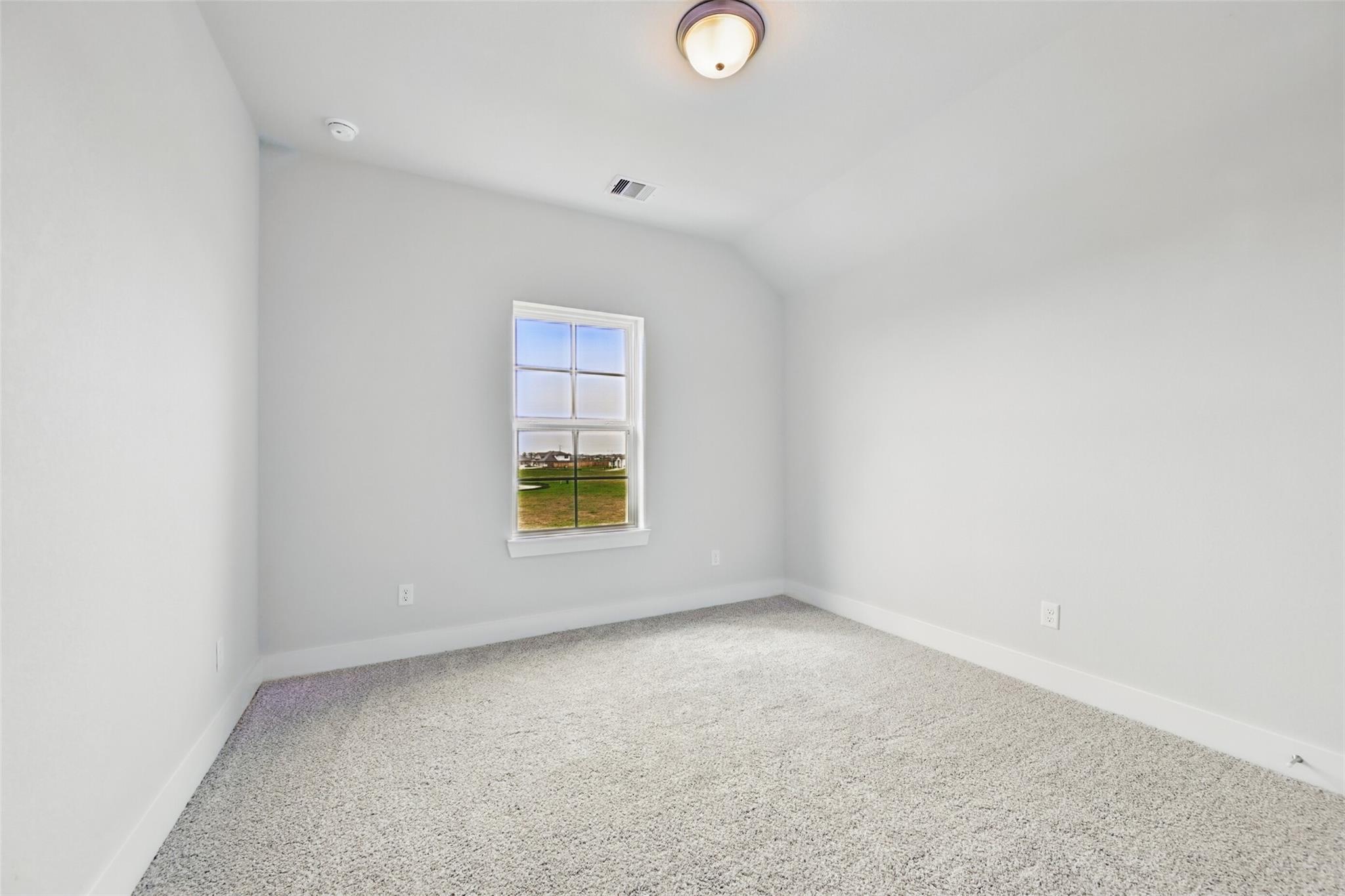Bright secondary bedroom with sloped ceiling, large window to green fields, gray carpet in 4-bed Davidson Homes The Philip A, Lago Mar TX