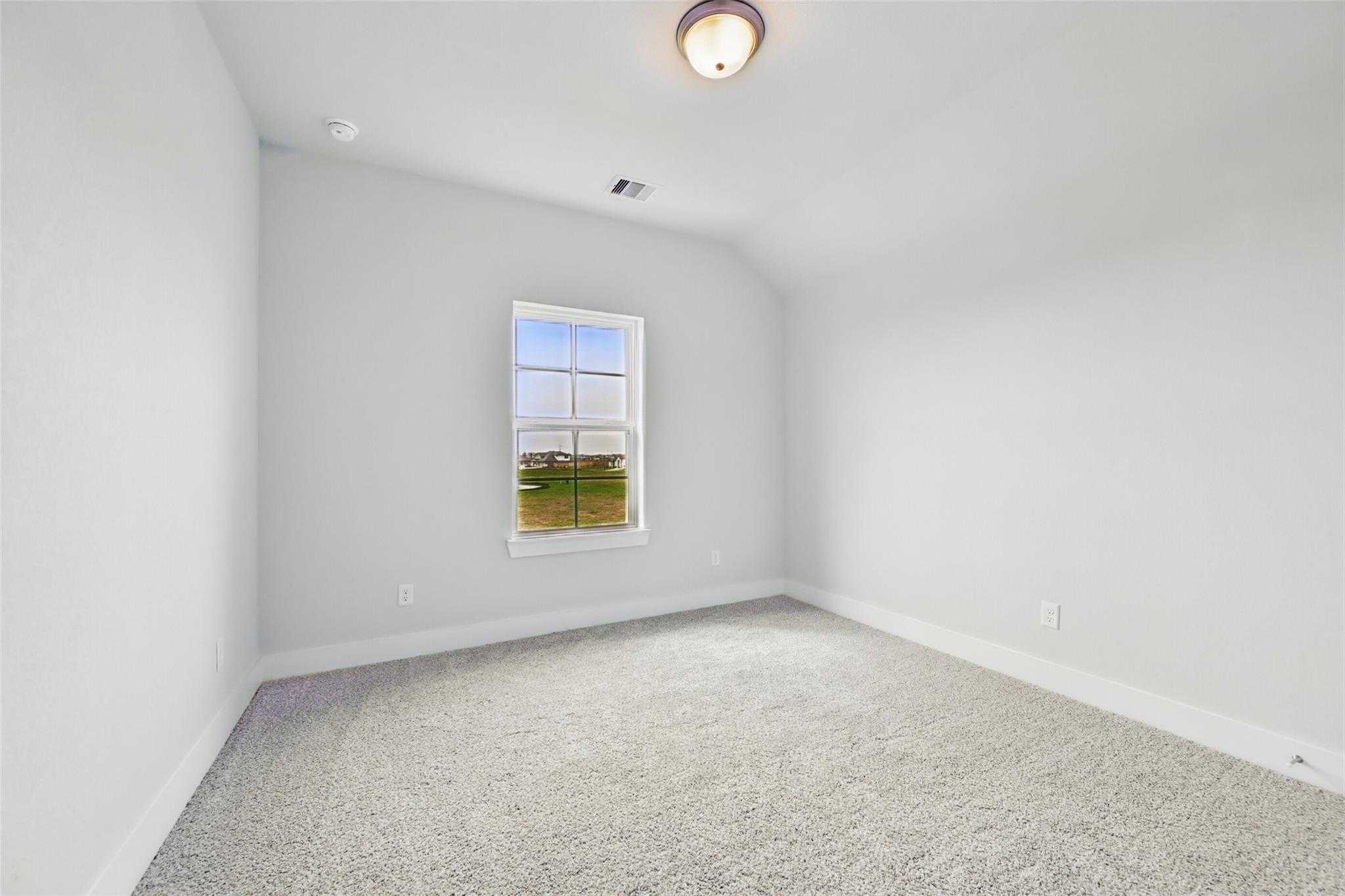 Bright secondary bedroom with sloped ceiling, large window to green fields, gray carpet in 4-bed Davidson Homes The Philip A, Lago Mar TX