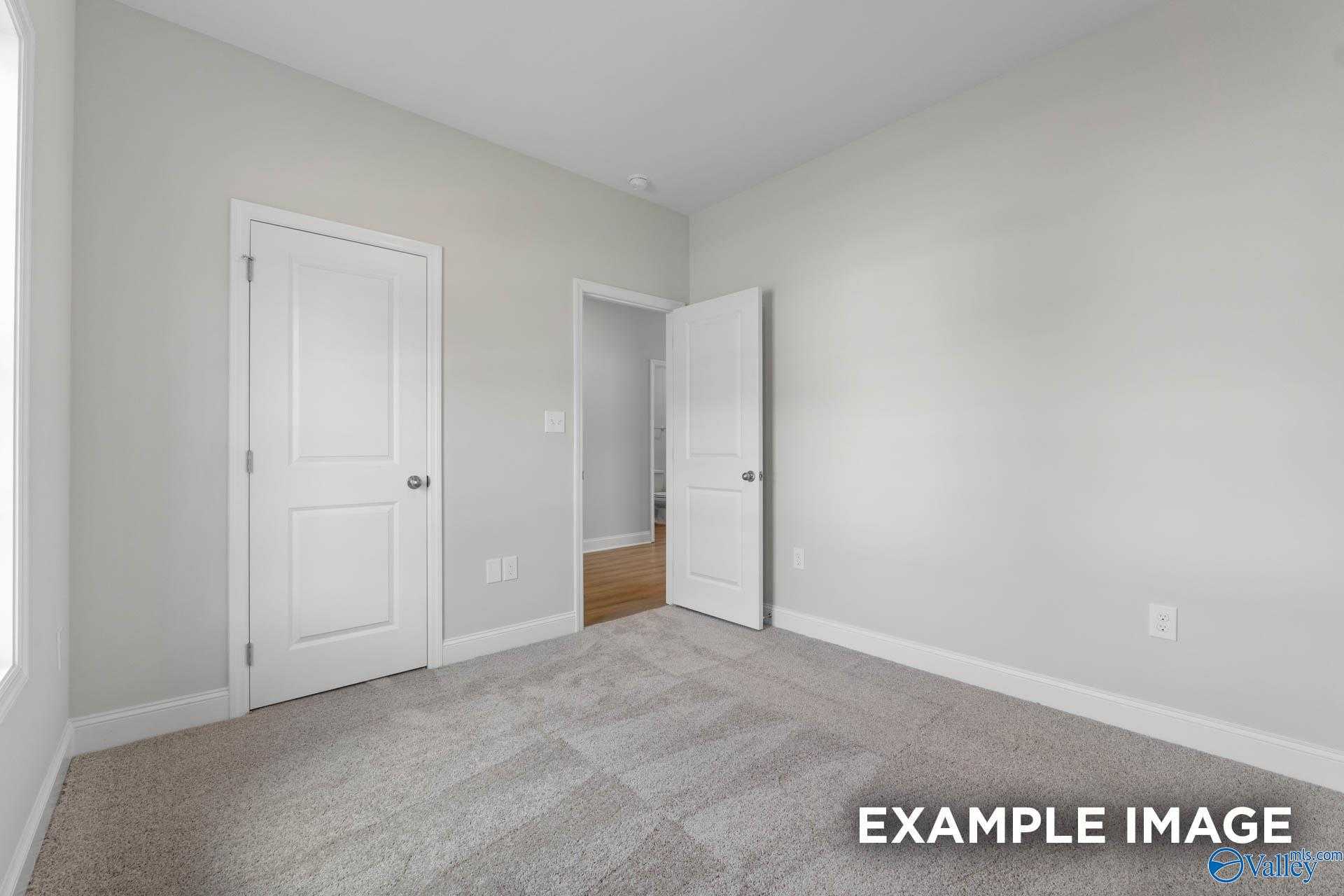 Bright secondary bedroom with light gray walls, gray carpet, and open doorway in Davidson Homes The Butler, Huntsville AL