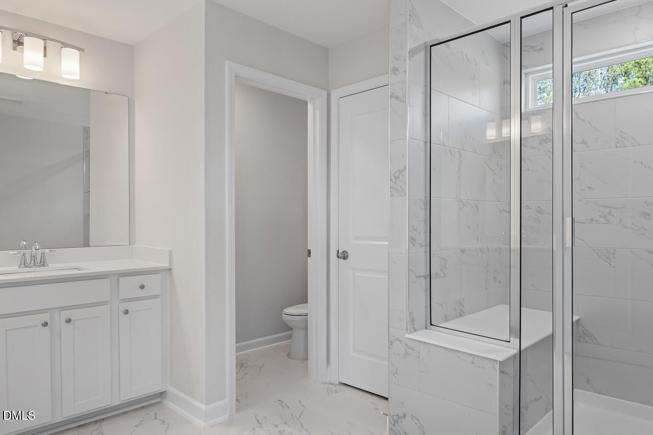 Modern master bathroom with white double vanity, frameless glass shower, subway tile walls in Davidson Homes The Graham, Fuquay-Varina, NC