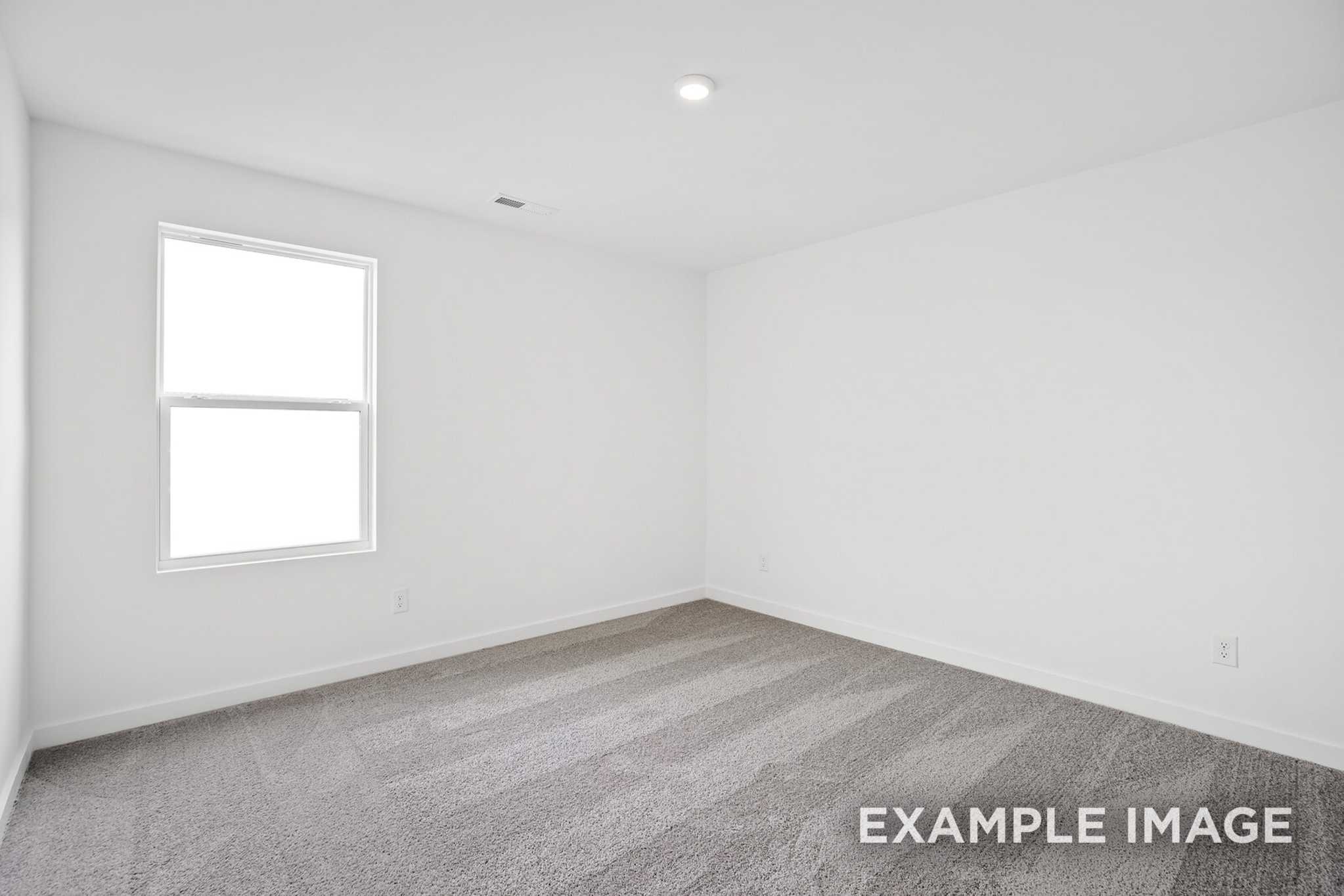 Spacious empty bedroom in The Murray B with white walls, large window, recessed lighting, and neutral carpet