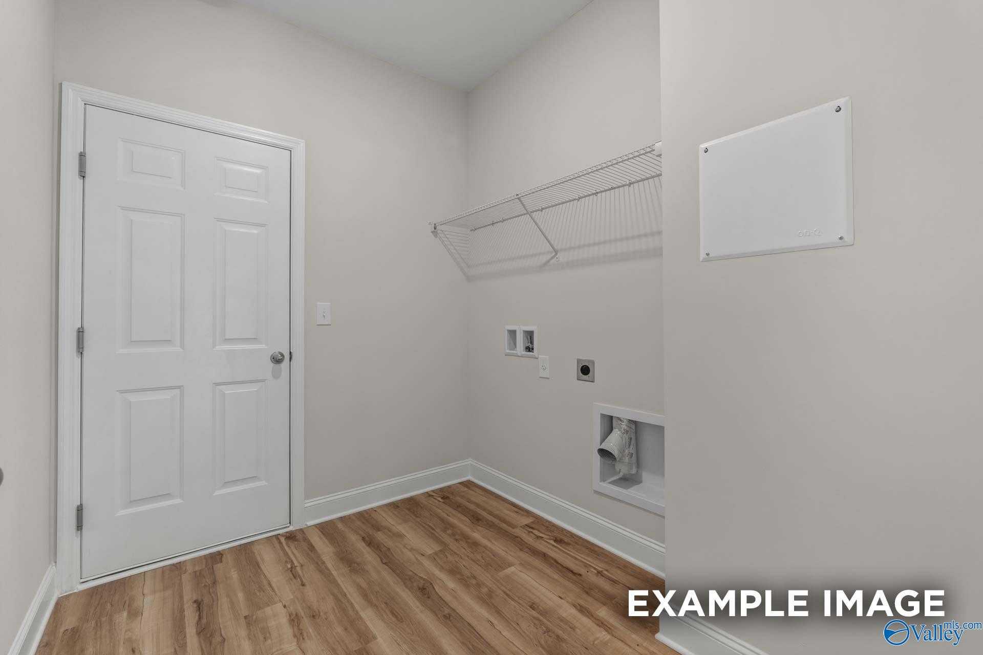 Functional laundry room with washer/dryer hookups, wire shelving, and hardwood floors in Davidson Homes The Butler, Toney, Alabama