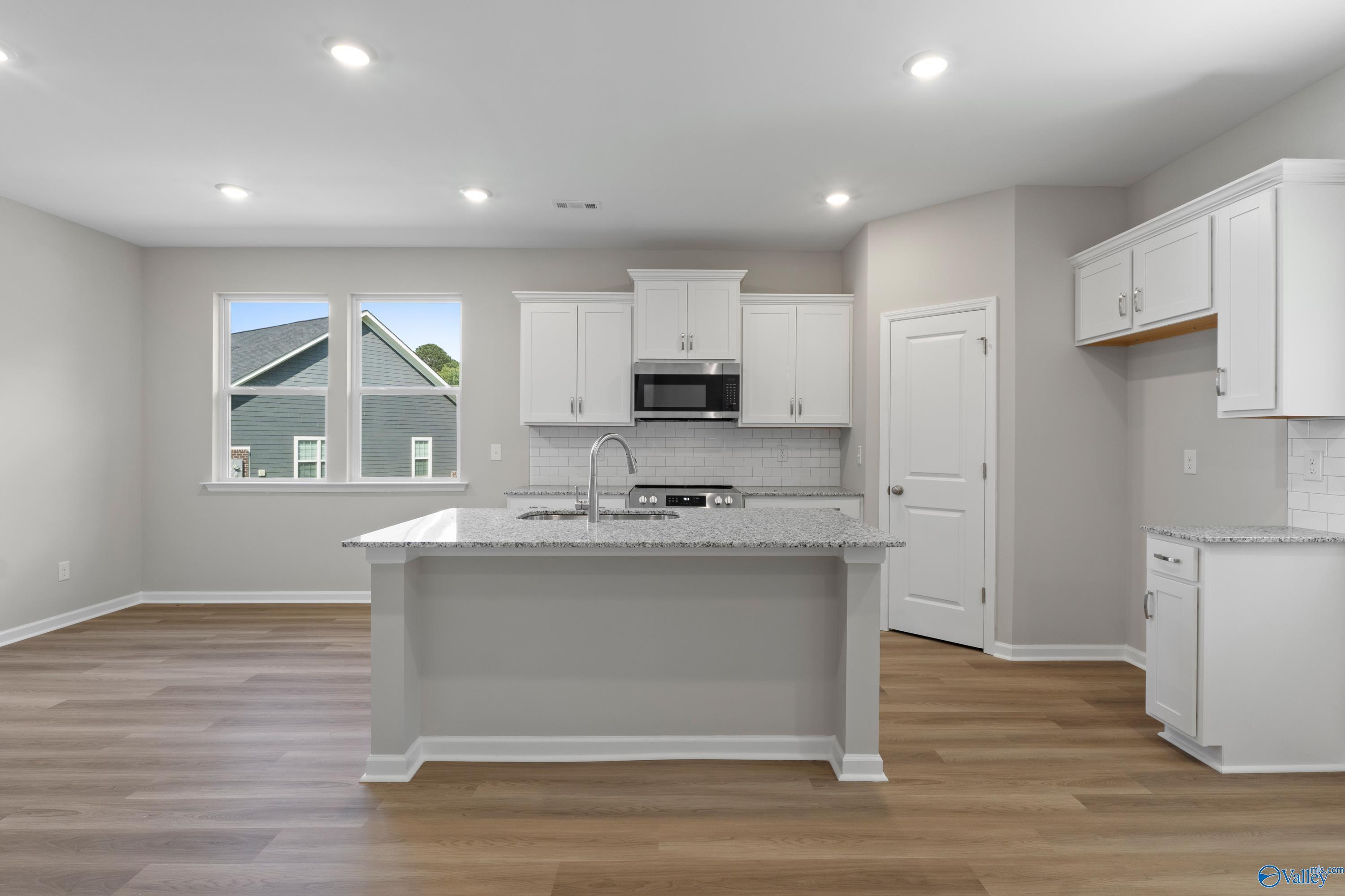 Modern kitchen featuring white shaker cabinets, quartz island, stainless appliances in Davidson Homes The Polaris, Fayetteville, TN