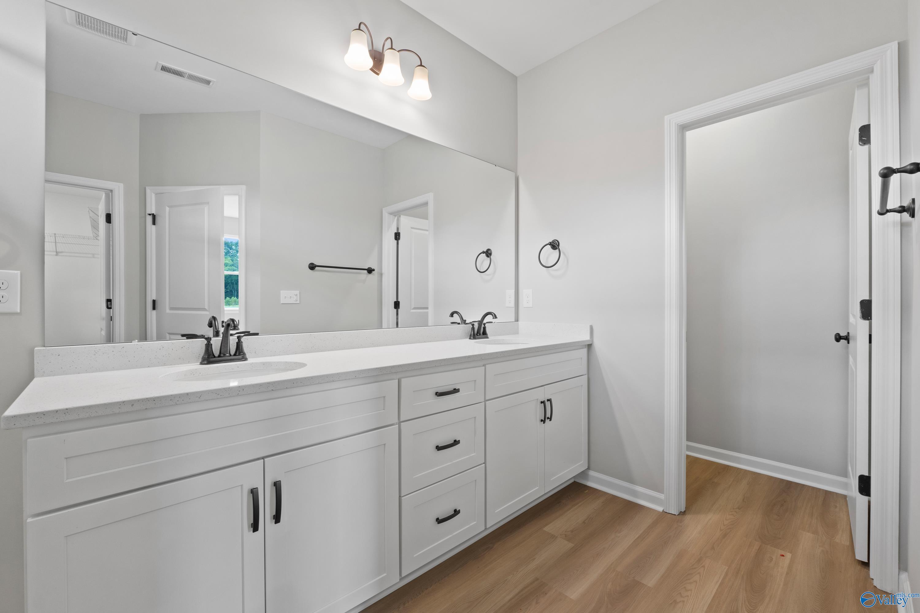 Modern master bathroom with double vanity sinks, white shaker cabinets, and frameless mirror in Davidson Homes The Dorado, Huntsville AL