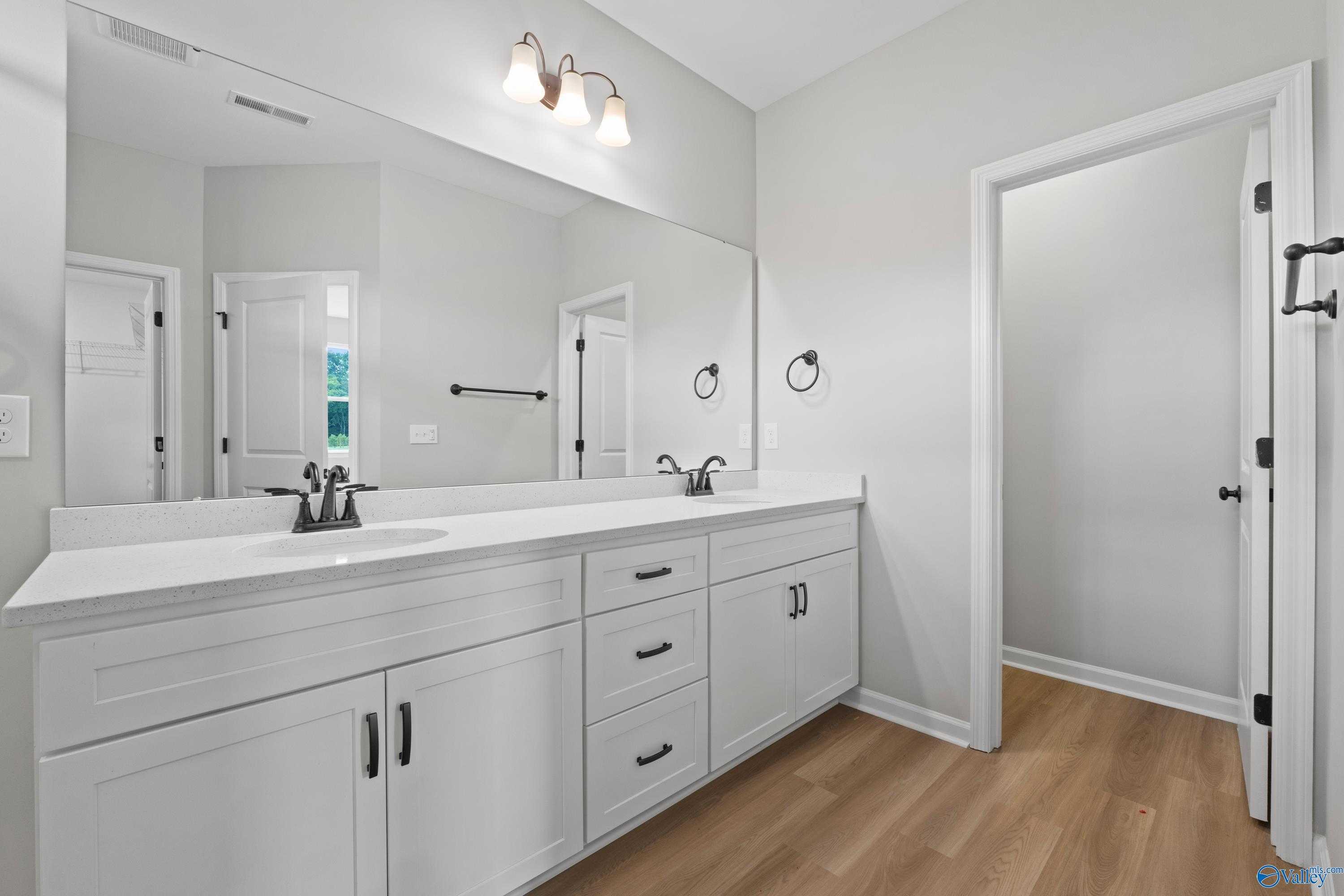 Modern master bathroom with double vanity sinks, white shaker cabinets, and frameless mirror in Davidson Homes The Dorado, Huntsville AL