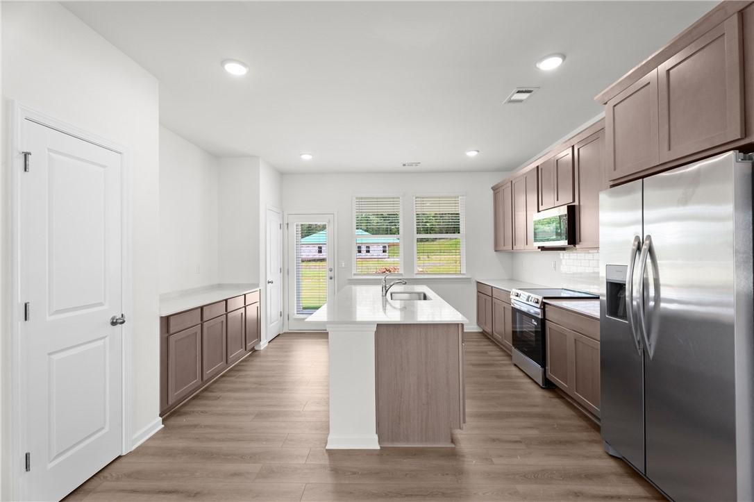 Modern kitchen with center island and stainless steel appliances in The Stella D floor plan by Evermore Homes in Silver Oak.