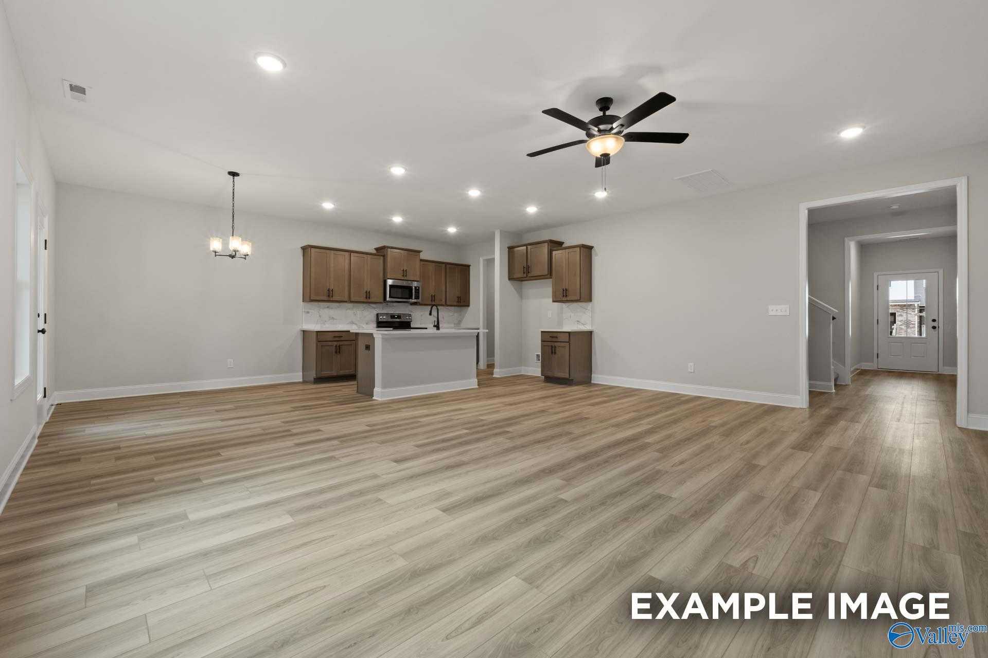 Open kitchen-living area with white cabinets, wood flooring, ceiling fan in The Camden D by Davidson Homes, Huntsville AL