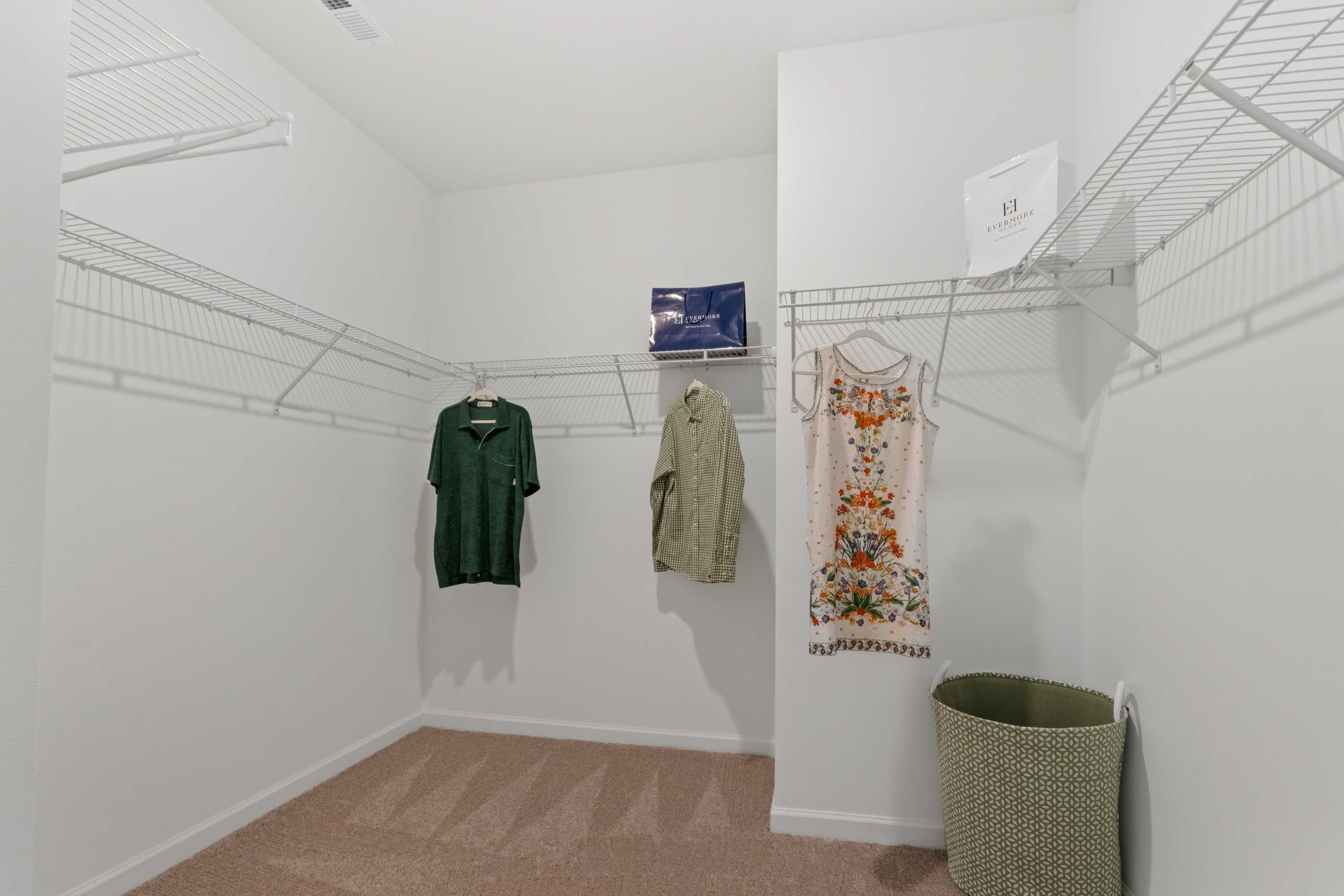 Spacious walk-in closet at Evergreen Mill in Madison Alabama with wire shelving, hanging clothes and storage basket