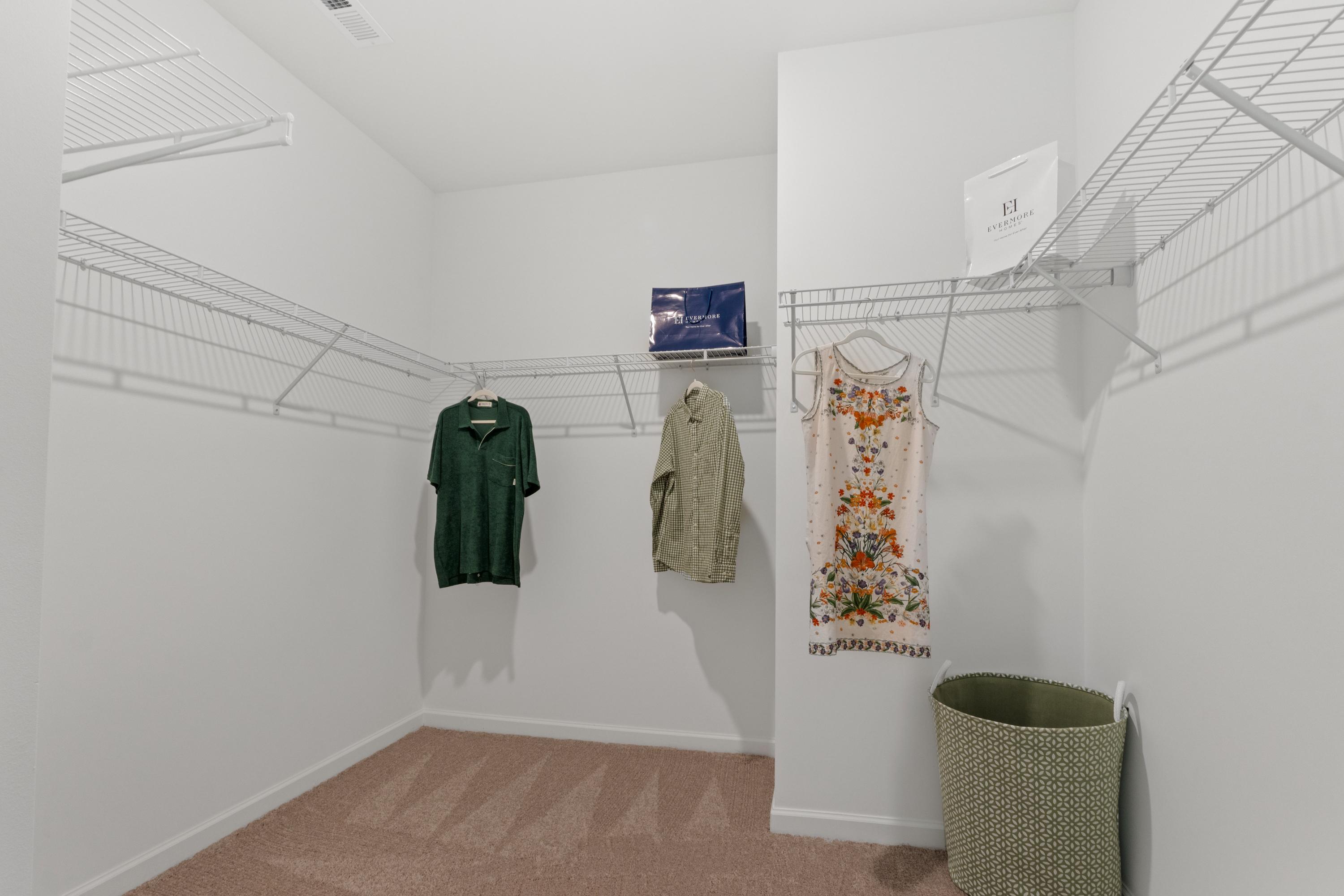 Spacious walk-in closet at Evergreen Mill in Madison Alabama with wire shelving, hanging clothes and storage basket