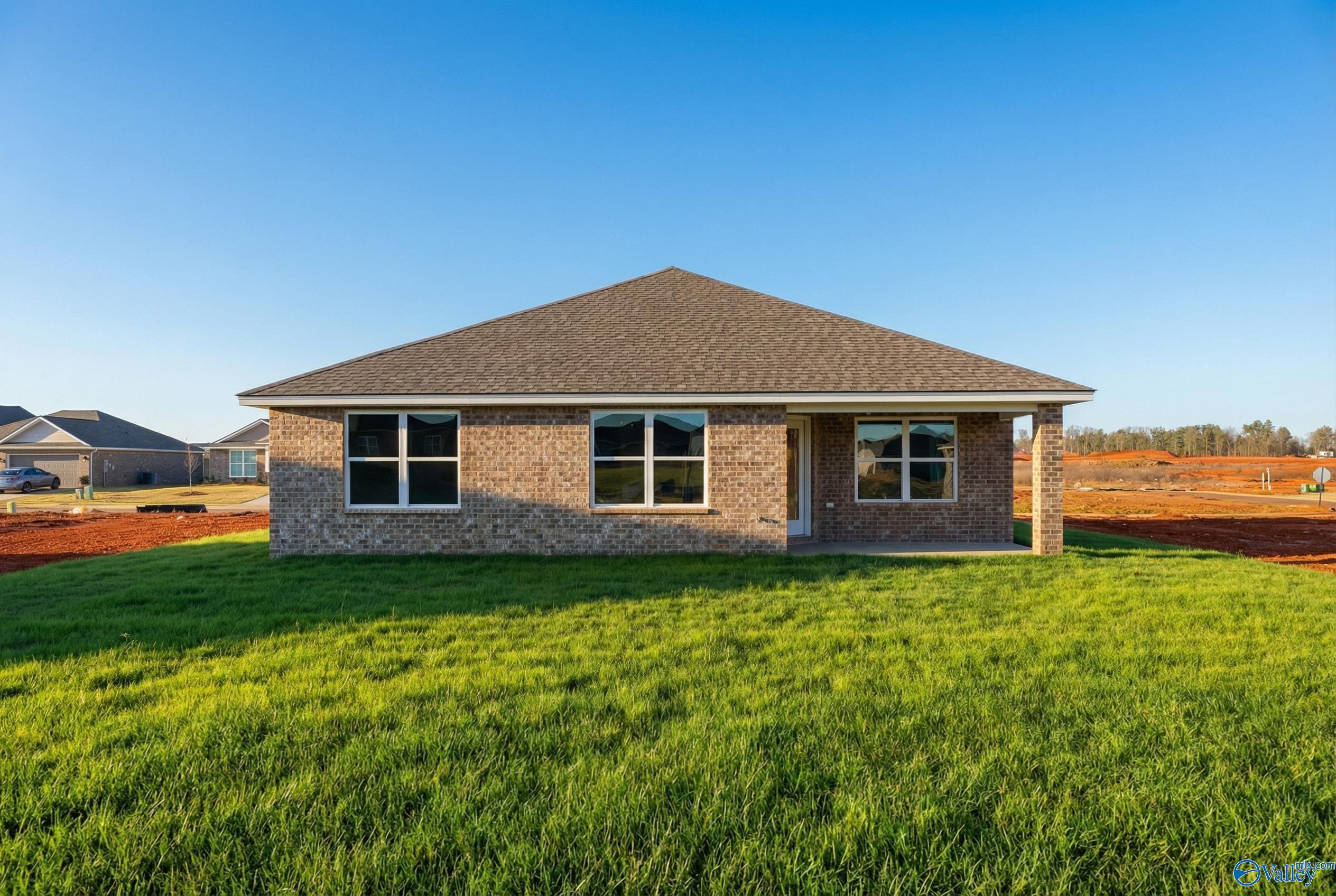The Franklin single-story brick home by Davidson Homes, covered front porch, large windows, lush green lawn in Heritage Lakes, New Market, Alabama