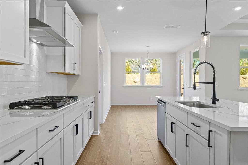 Modern white kitchen with quartz island, gas cooktop, subway tile backsplash in Davidson Homes The Edison B, Loganville, GA