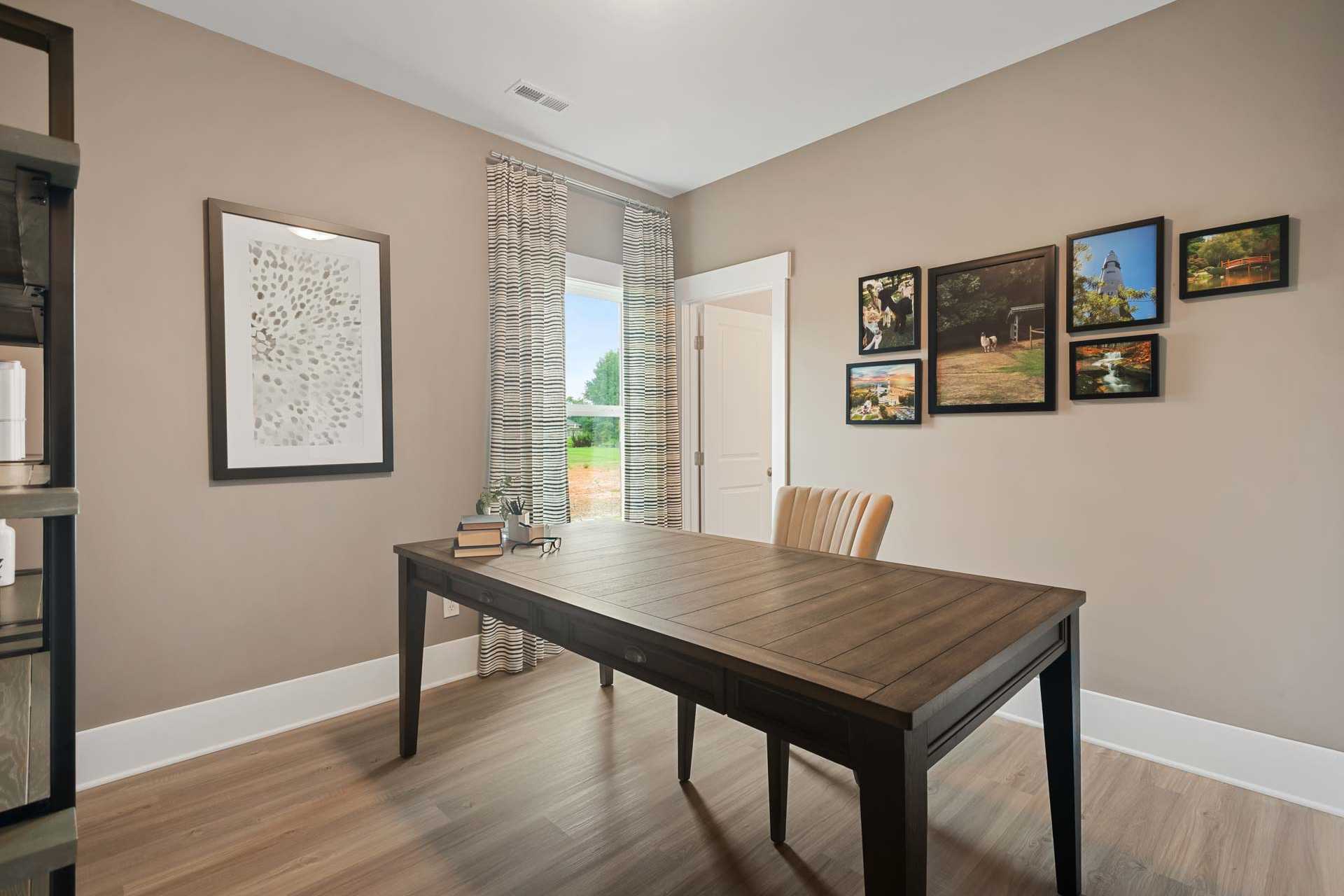 Cozy home office at Durham Farms in Harvest, Alabama with wooden desk, beige walls, hardwood floors, and window view