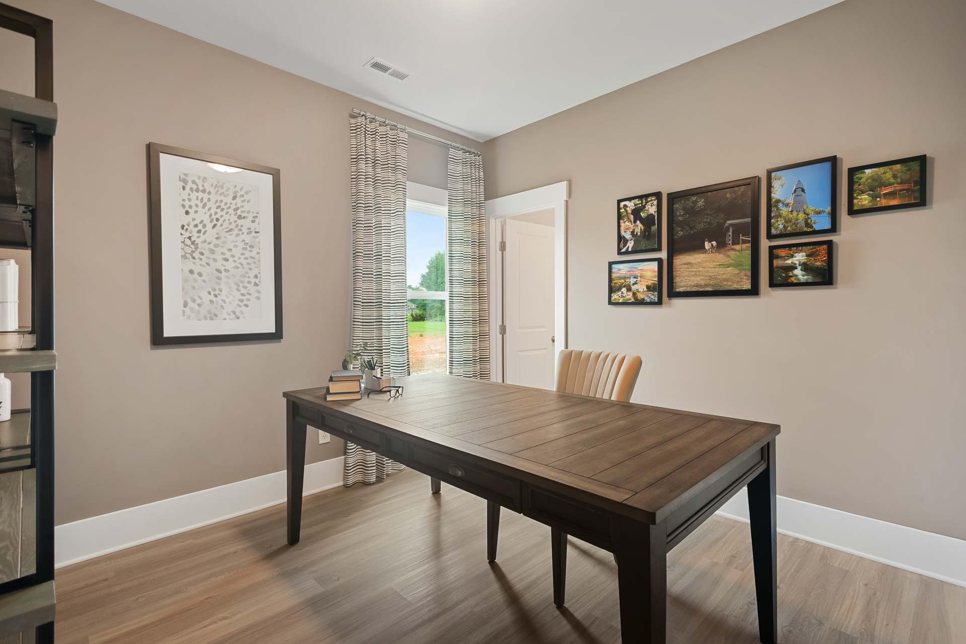 Cozy home office at Durham Farms in Harvest, Alabama with wooden desk, beige walls, hardwood floors, and window view