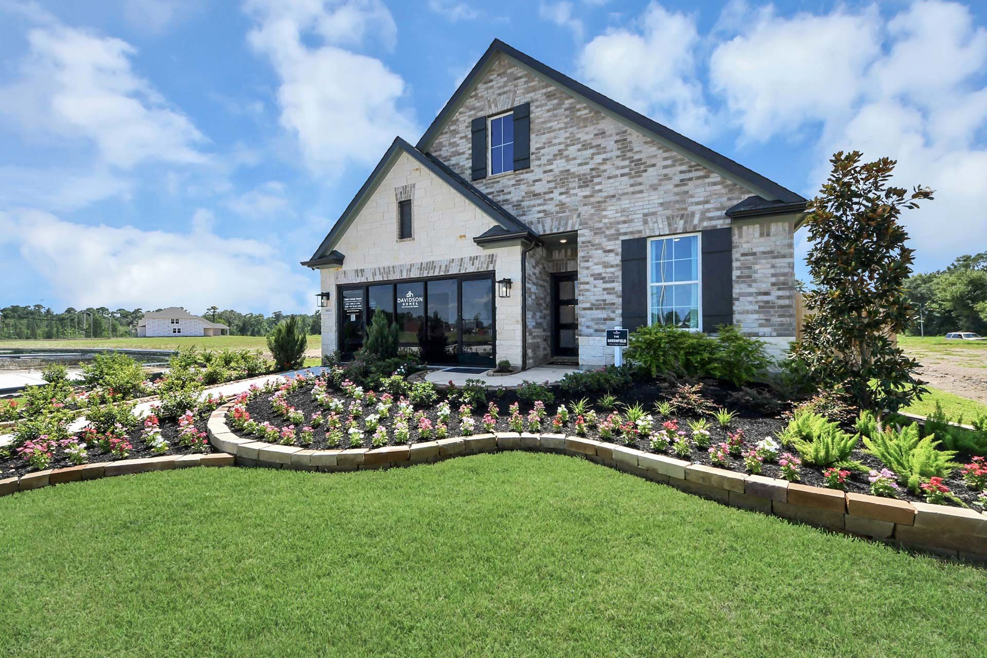 Davidson Homes model at Enclave at Newport in Crosby, Texas featuring brick exterior and professionally landscaped garden.