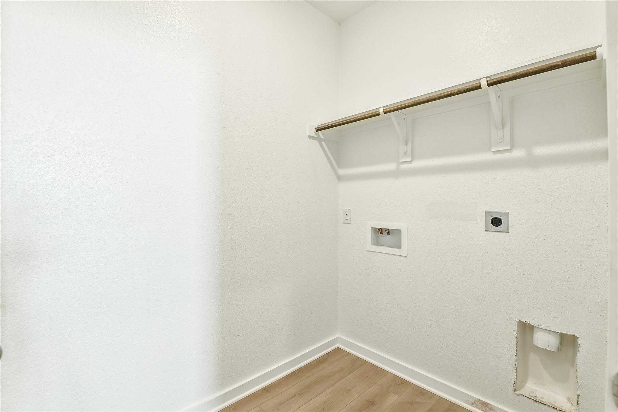 Modern laundry room with wooden shelves, hanging rod, washer-dryer hookups in 4-bedroom Davidson Homes Colorado F, Cleveland TX