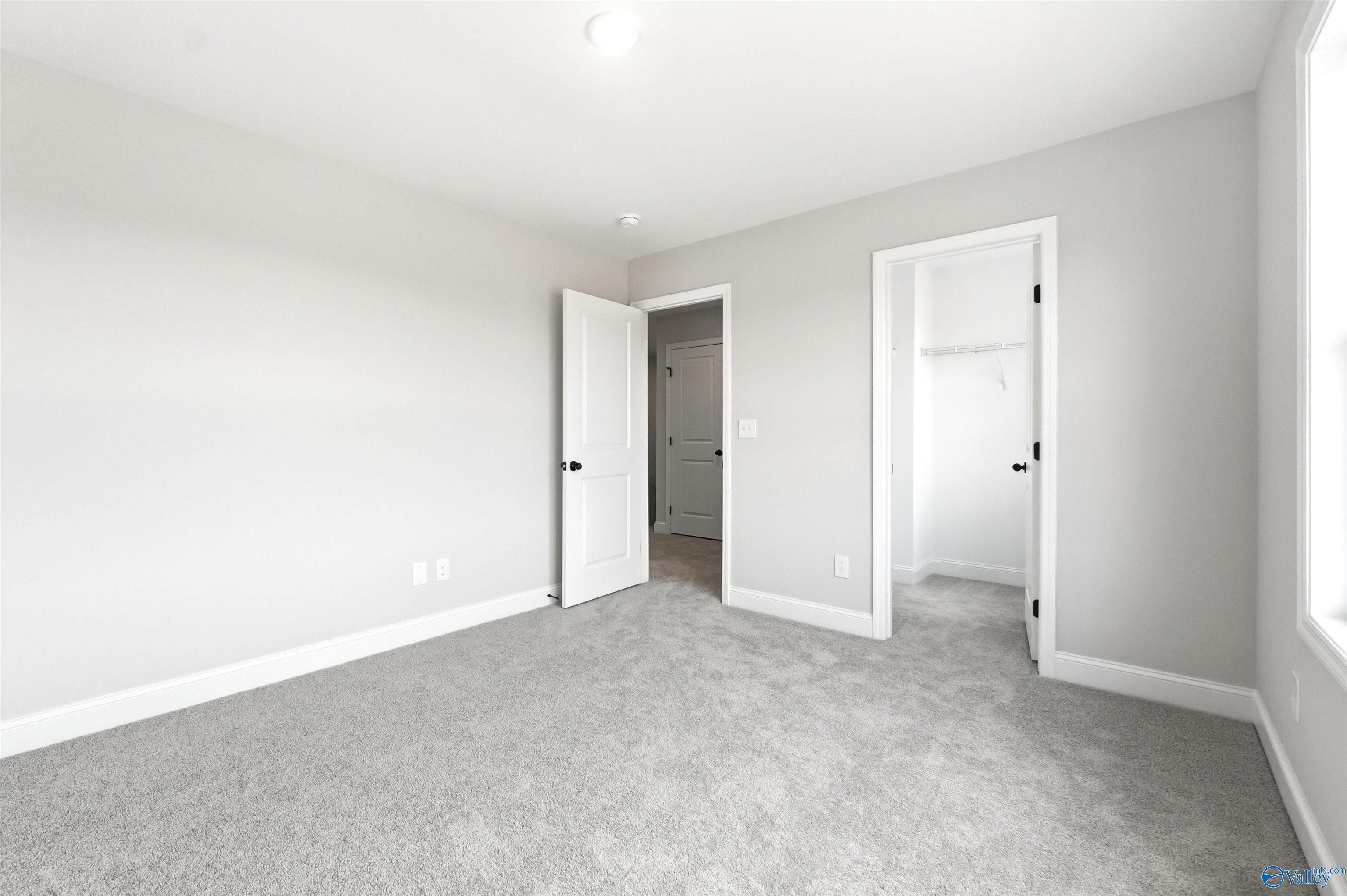 Spacious secondary bedroom with plush carpet and walk-in closet in Davidson Homes The Chelsea D floor plan, New Market, AL.