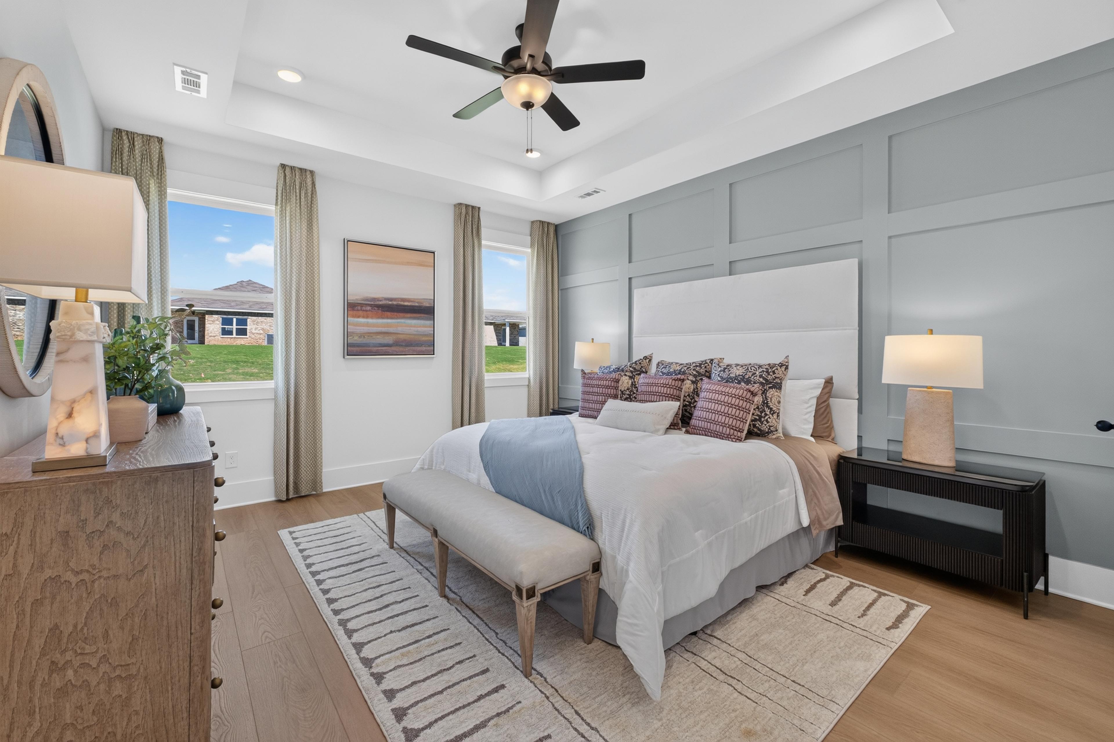 Primary bedroom with tray ceiling and accent wall at Evergreen Mill by Davidson Homes in Madison, Alabama
