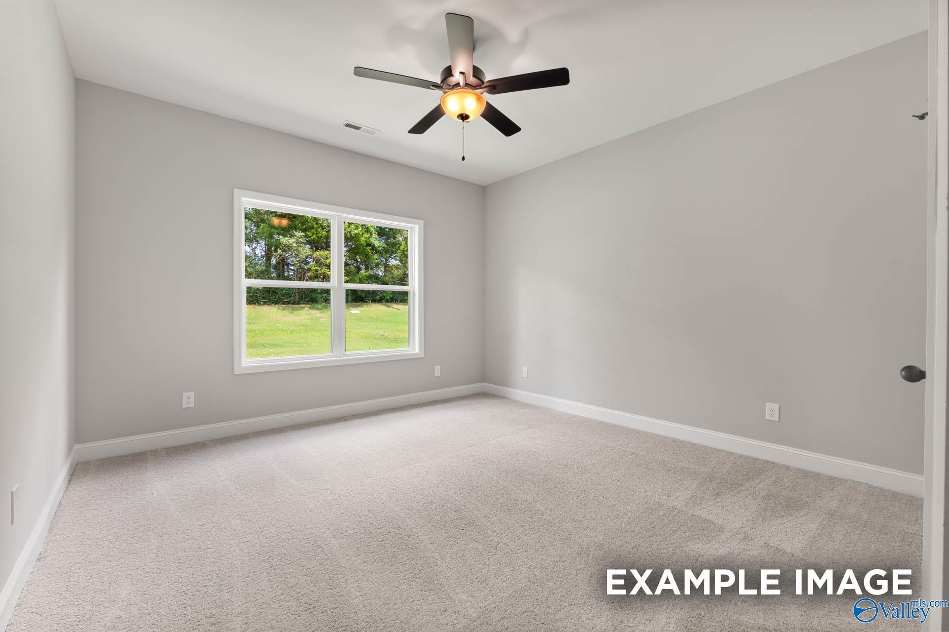 Bright secondary bedroom with ceiling fan and large window view of lush green lawn in Davidson Homes The Asheville C, Hazel Green AL