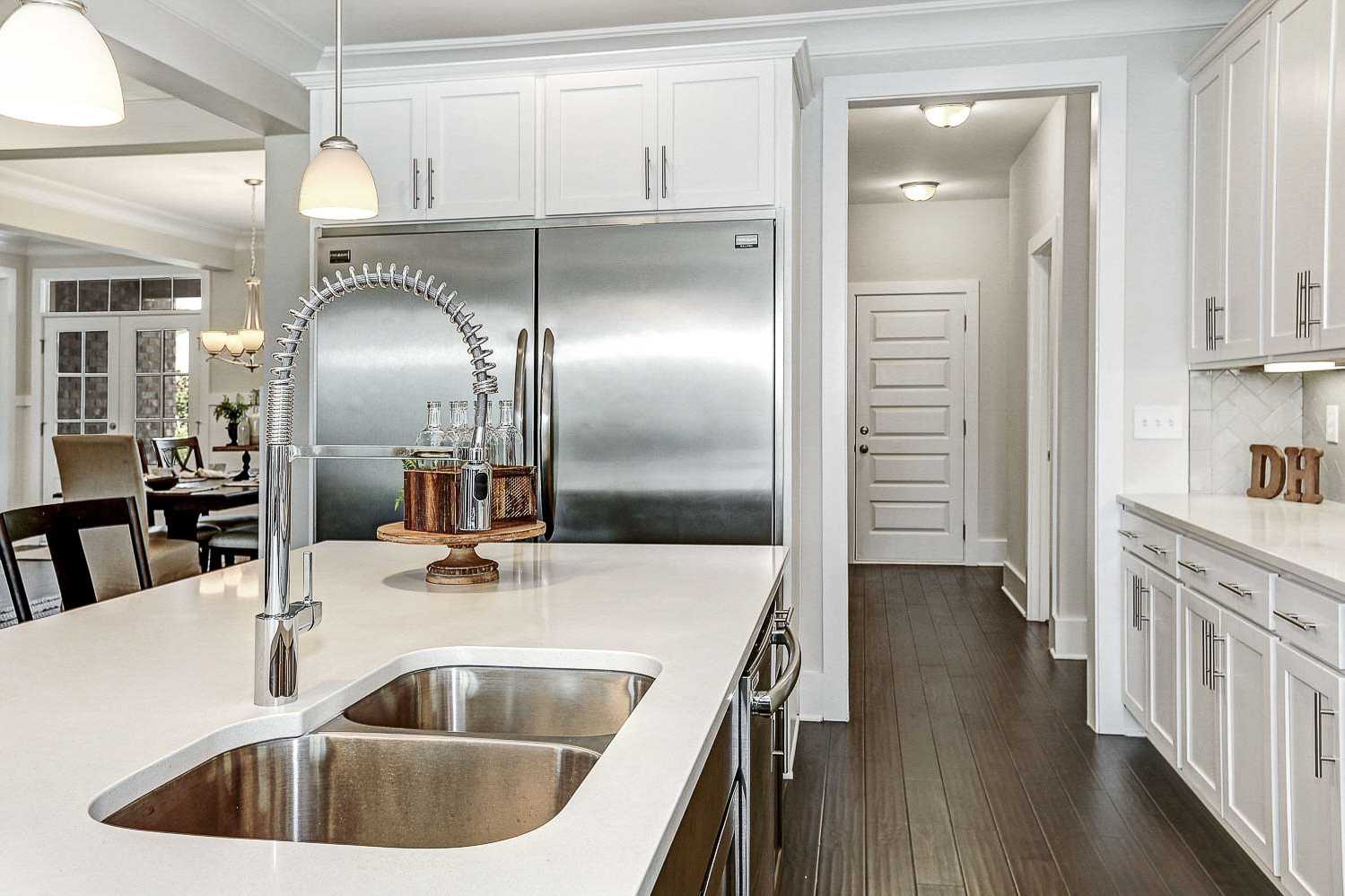 Spacious kitchen in The Finleigh by Davidson Homes featuring white cabinets, quartz island with double sink, and open dining area