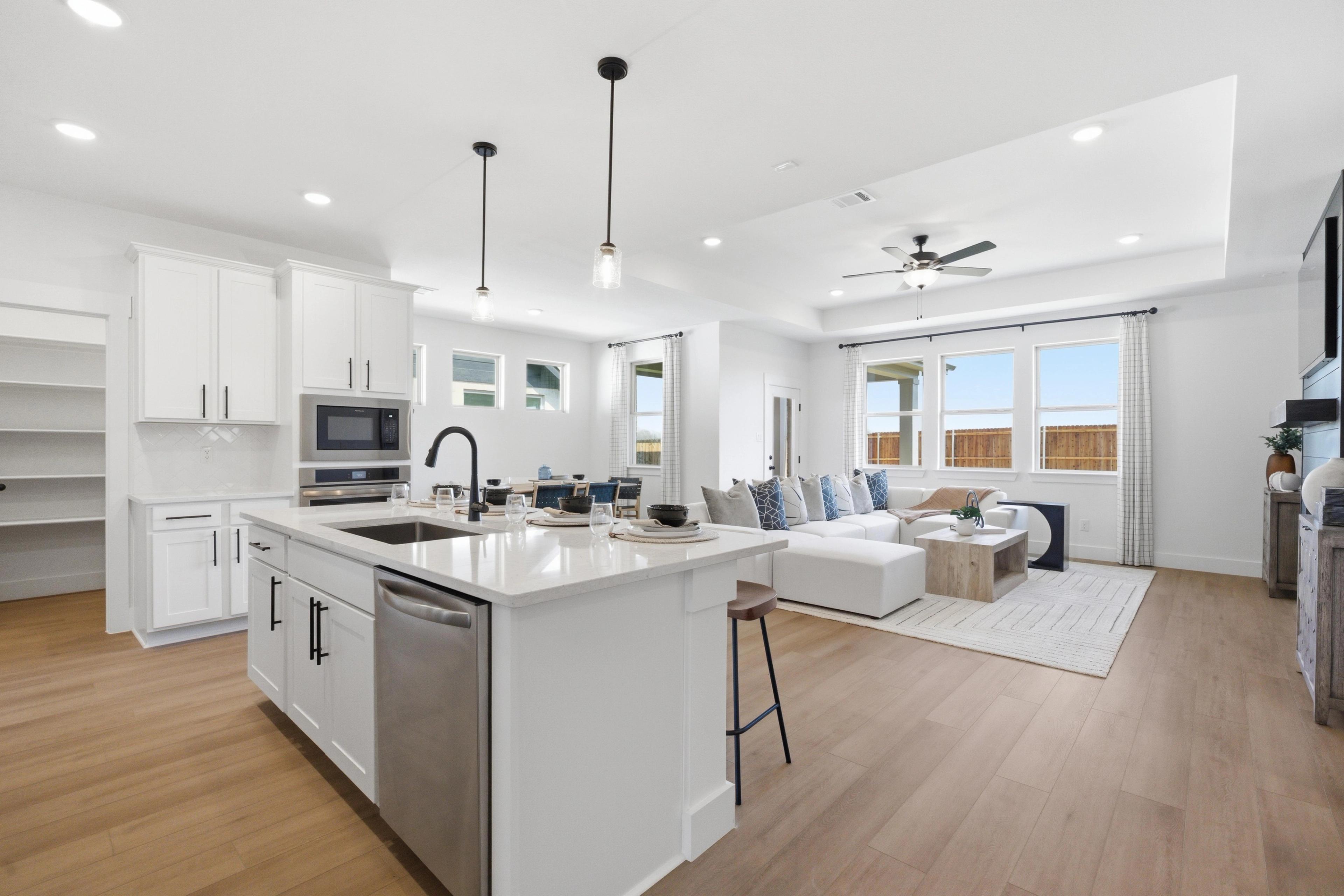 Spacious open-concept kitchen and living room in Mercer Meadows Royse City TX with white island hardwood floors pendant lights and sofa