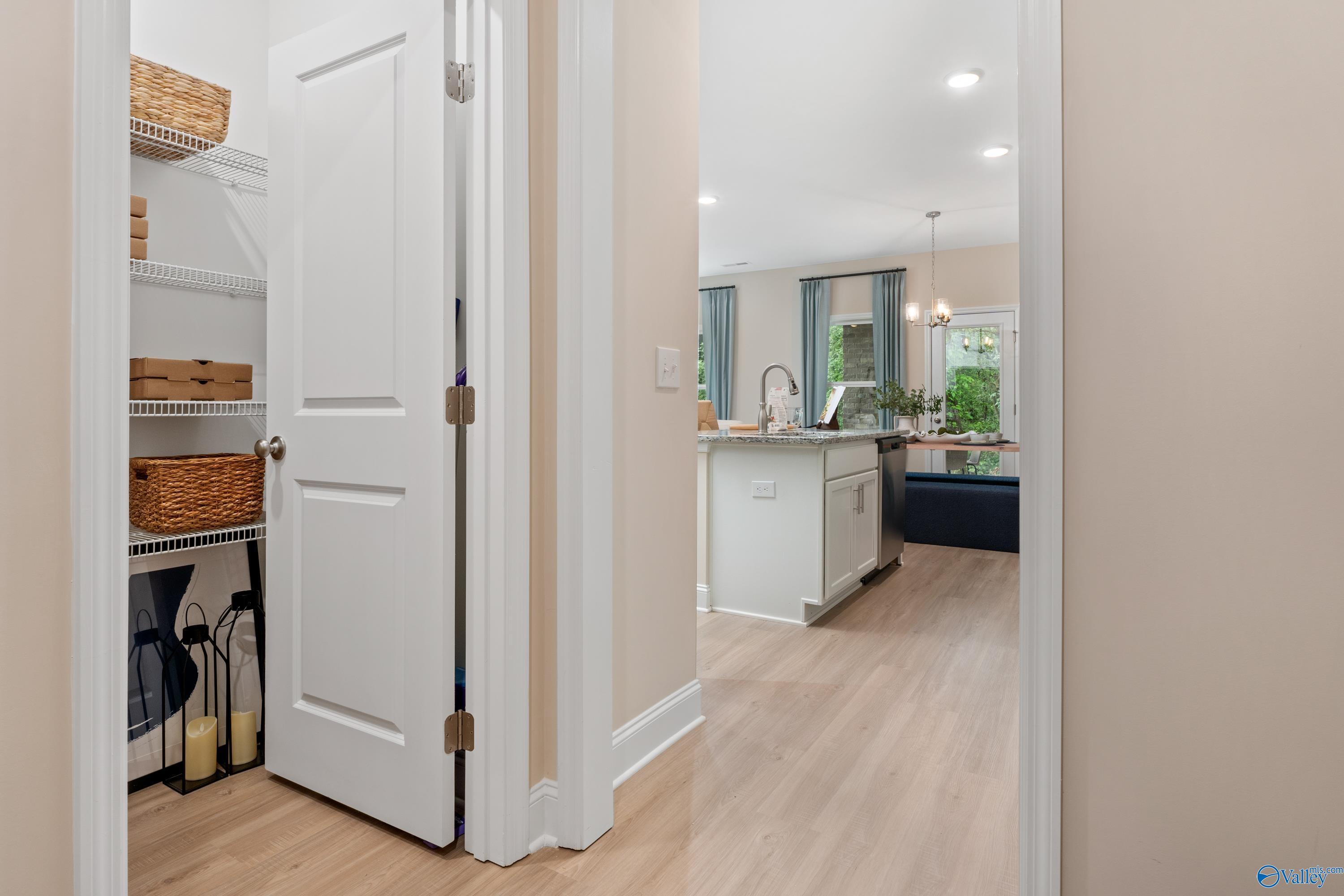 Spacious walk-in pantry with shelves, baskets and storage next to modern white kitchen island in Davidson Homes The Camden, Huntsville AL