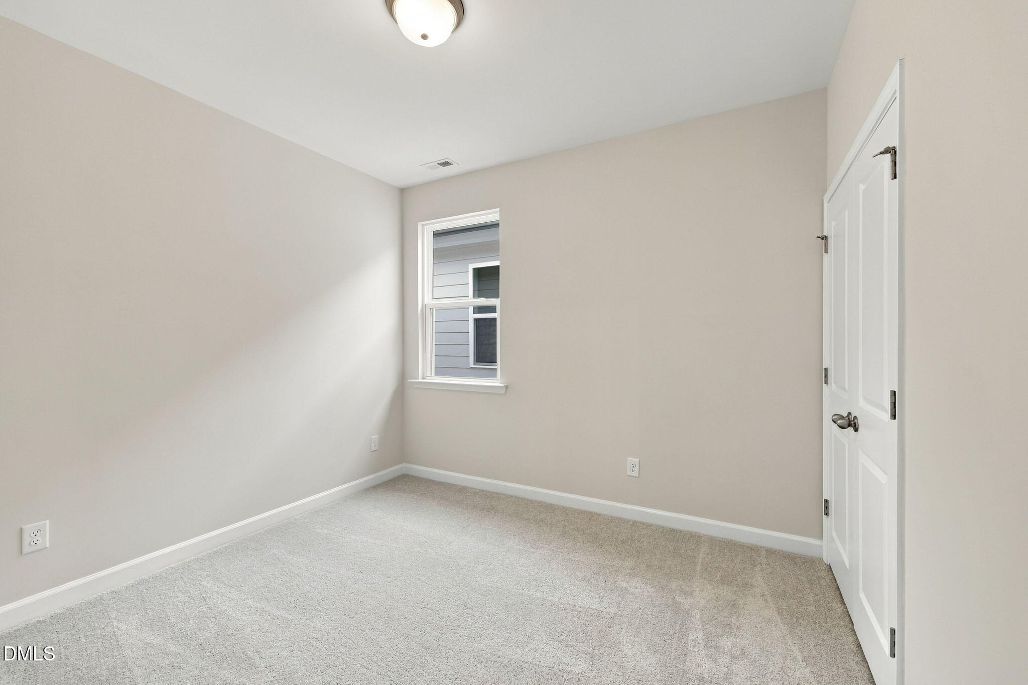 Bright carpeted bedroom with neutral walls, double closet doors, and window in Davidson Homes The Alexander B, Knightdale, NC