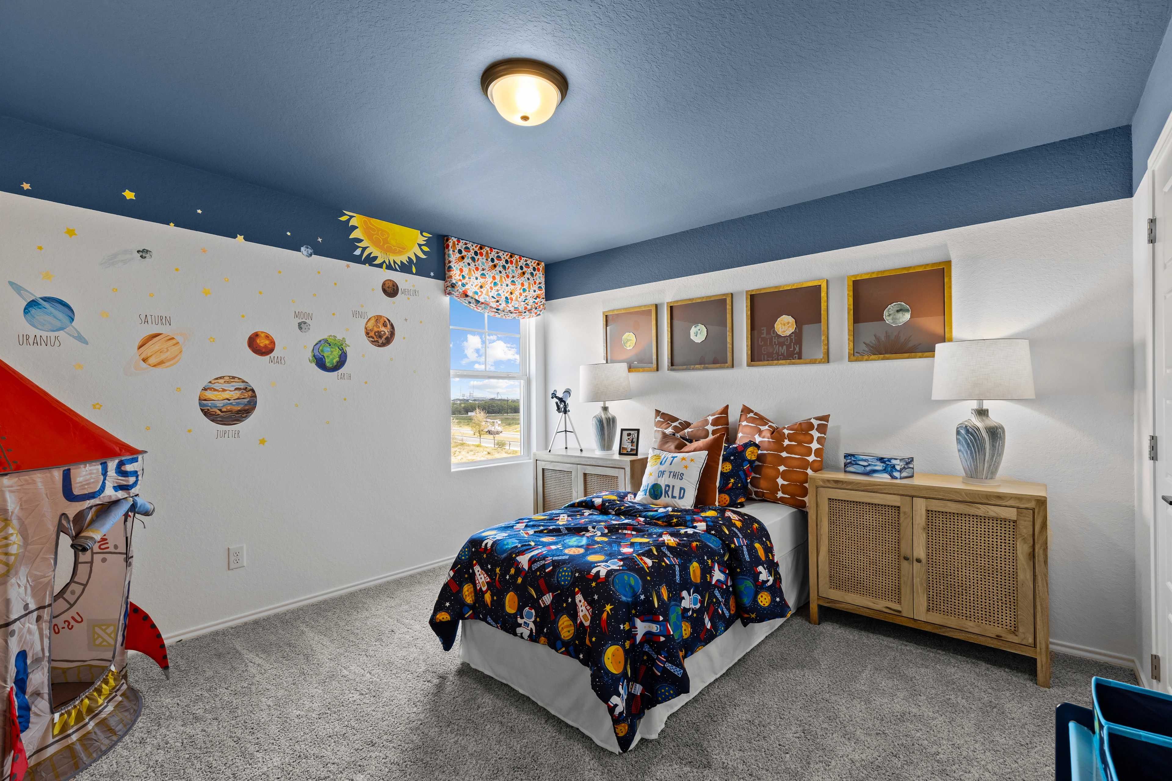 Space-themed boy's bedroom at Hickory Ridge in Elmendorf TX by Davidson Homes featuring solar system decals, rocket accents, and galaxy bedding