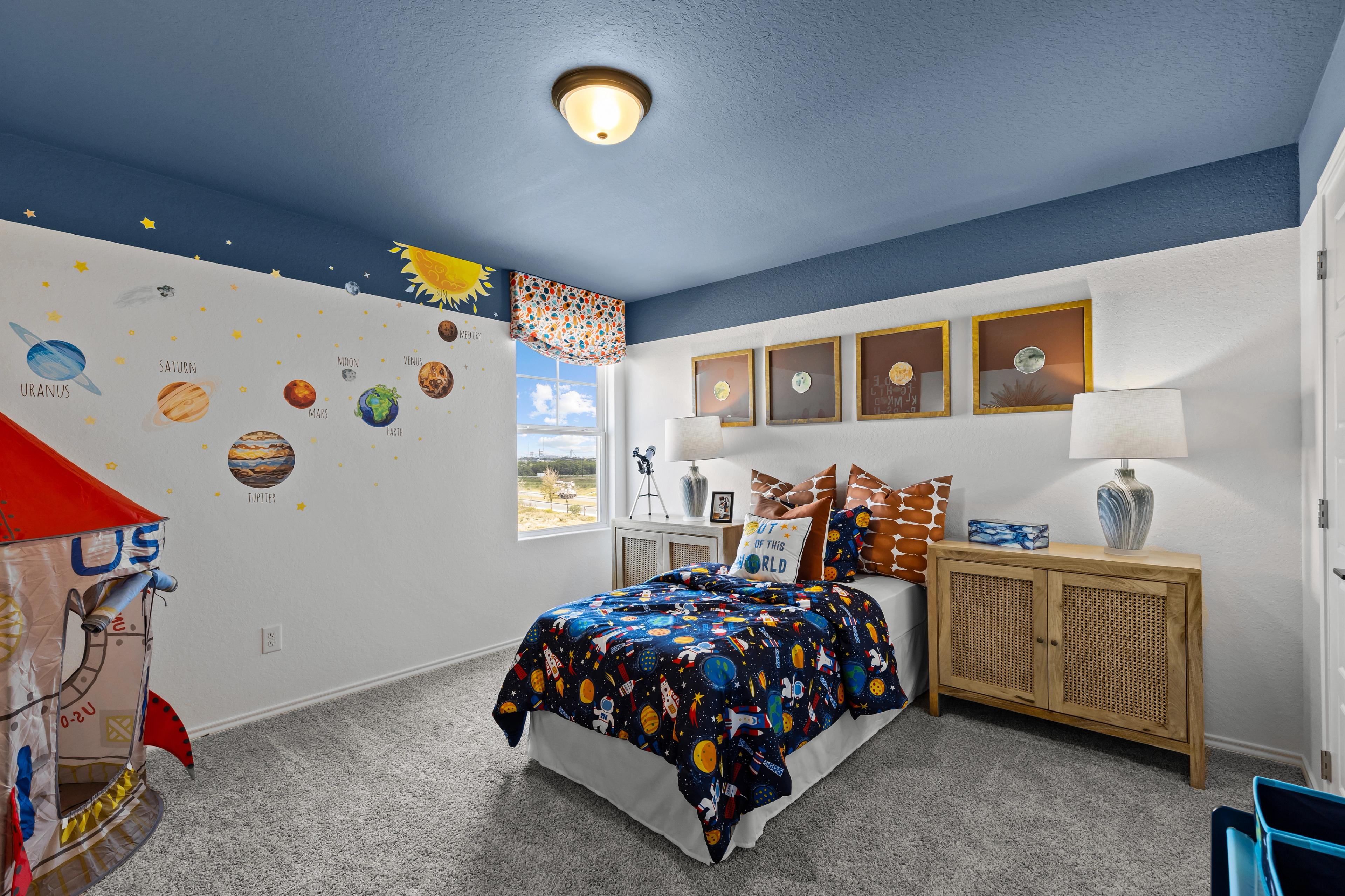 Space-themed child's bedroom in The Douglas F by Davidson Homes, San Antonio, with blue ceiling, solar system decals, rocket mural, and galaxy bed