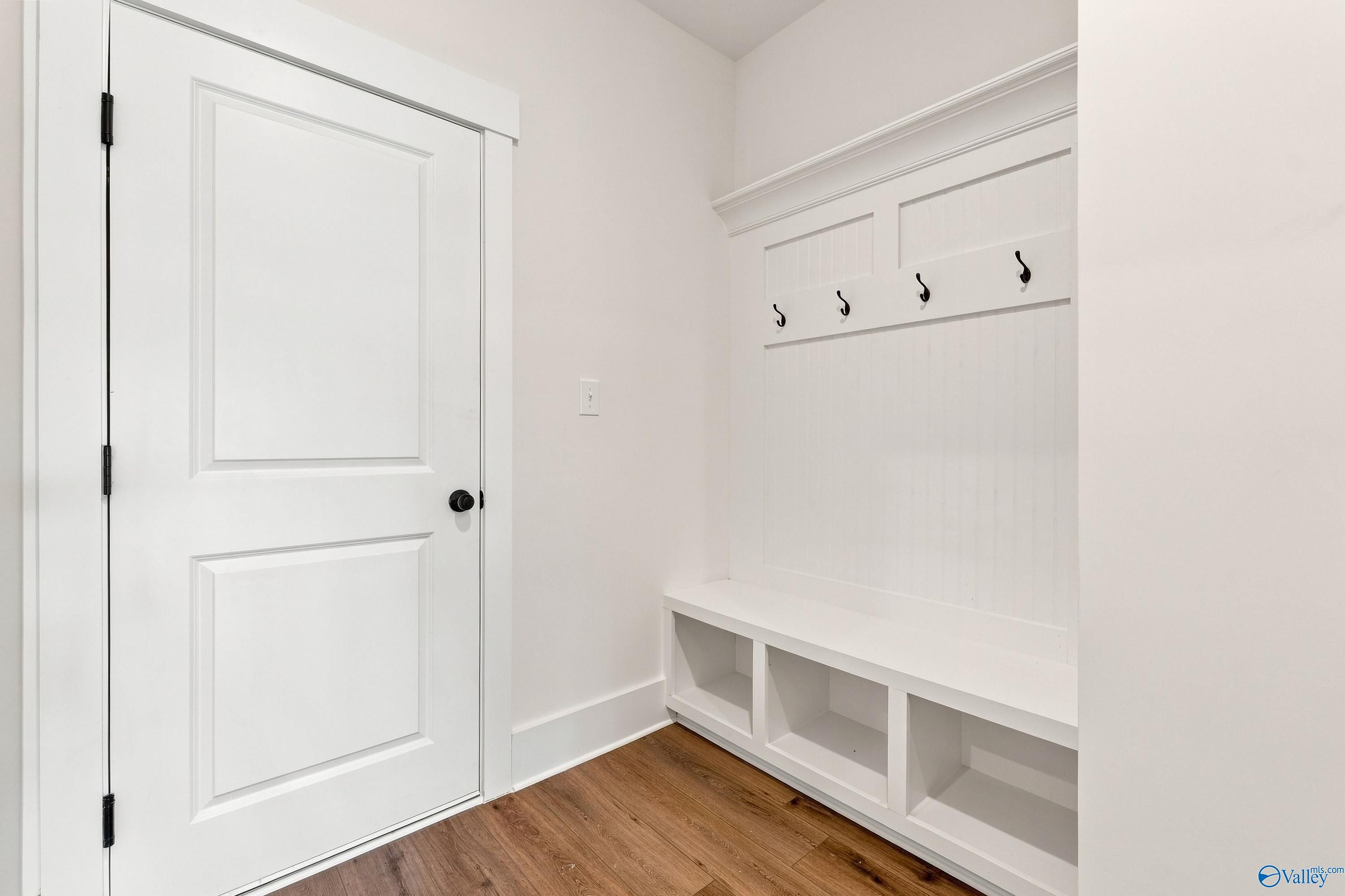White mudroom bench with coat hooks and storage cubbies in The Valencia floor plan at Riverton Preserve, Huntsville.