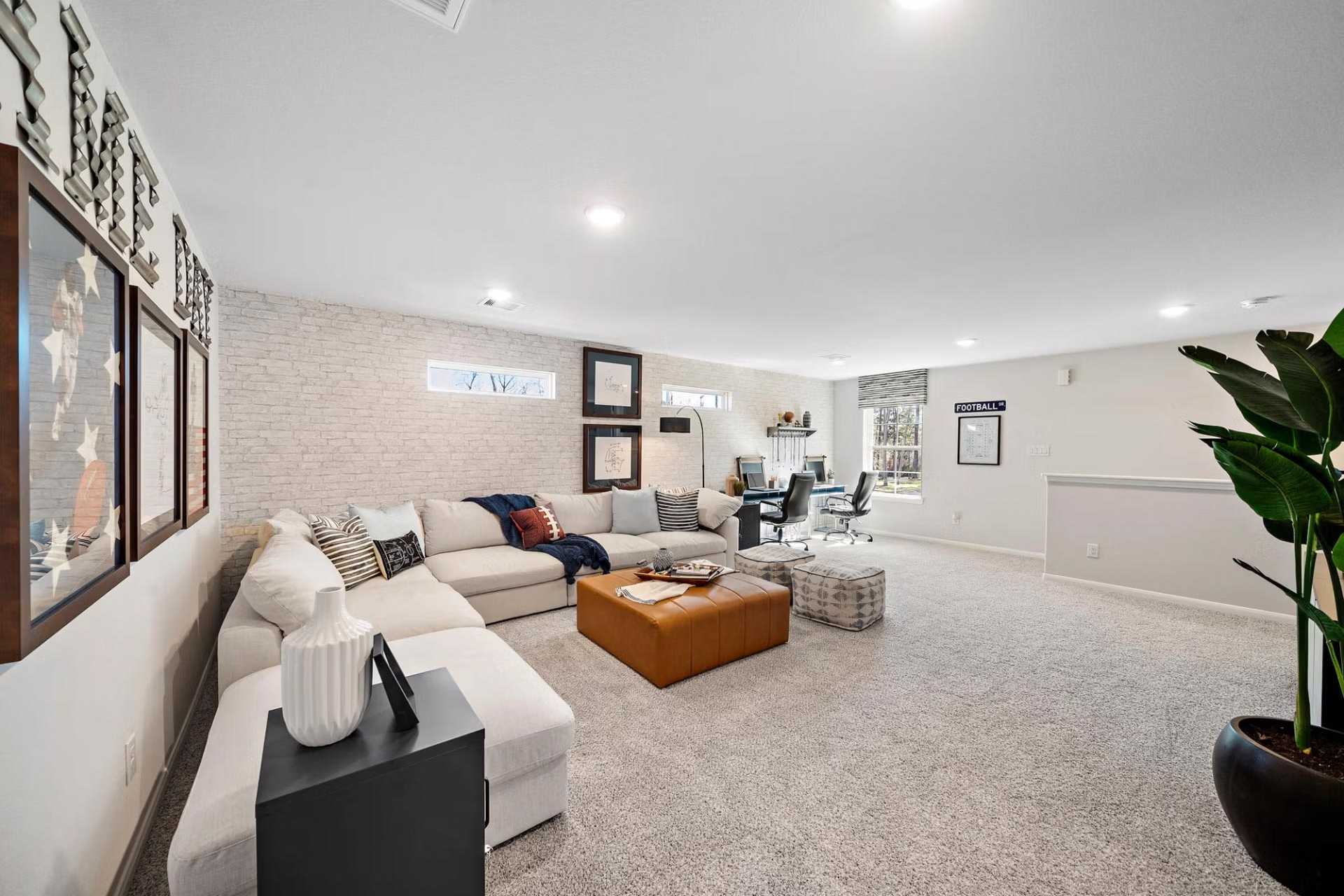 Spacious family room at Saddle Creek Ranch in Cibolo TX by Davidson Homes with L-shaped sofa, leather ottoman and built-in bookshelves