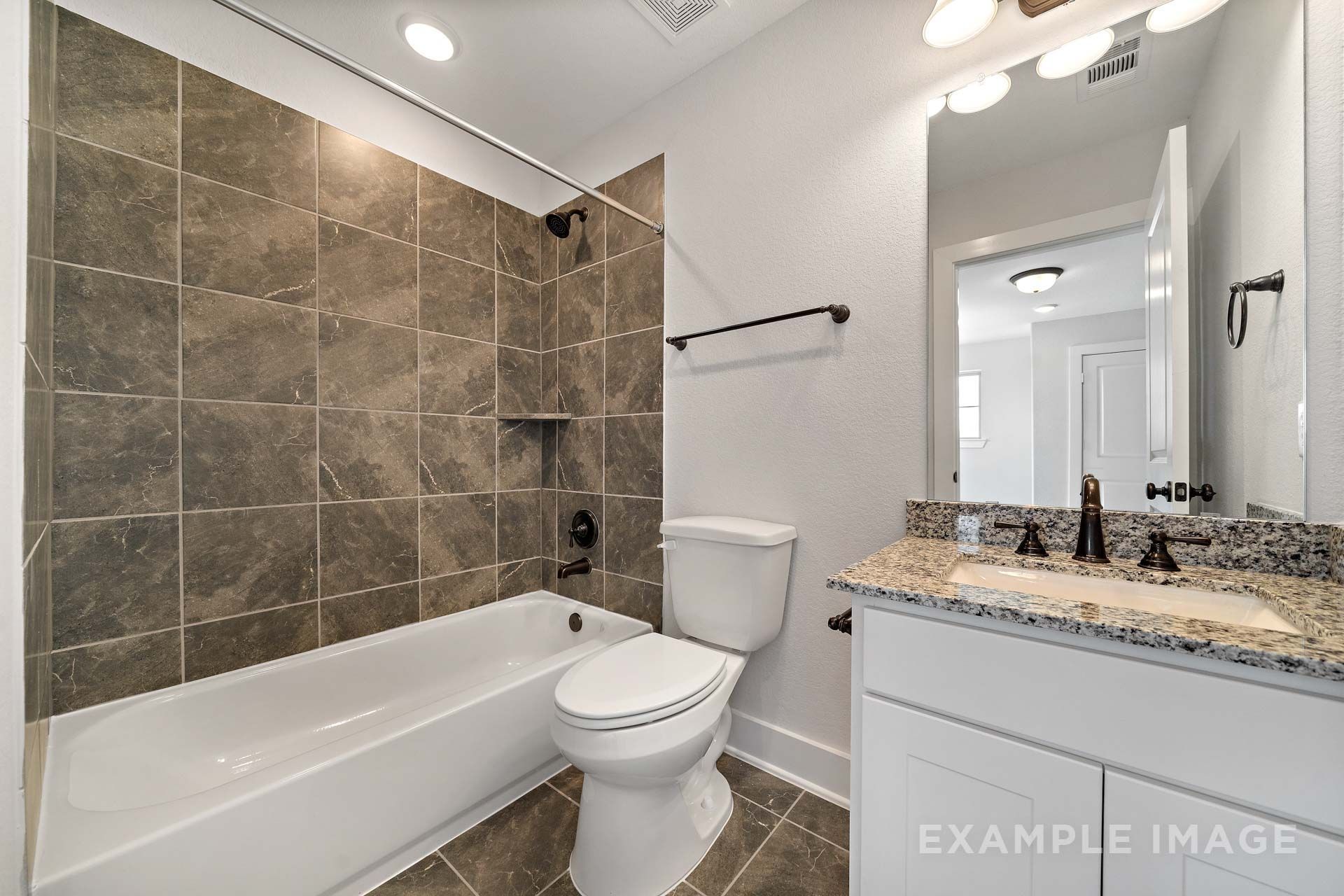 Bathroom in The Victoria by Davidson Homes featuring tiled tub shower, granite vanity, and white cabinetry in Texas City, TX