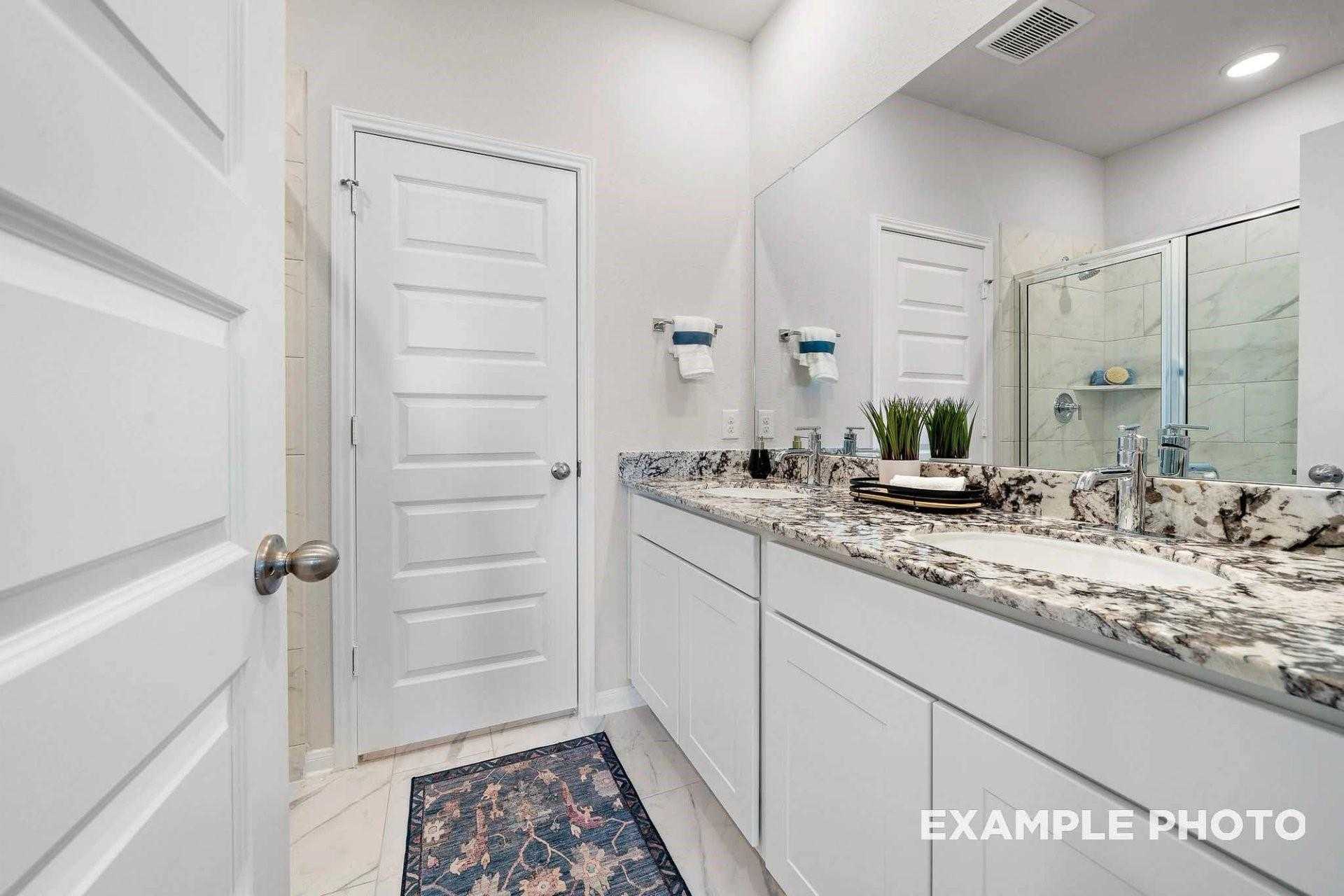 Modern white bathroom with double vanity, quartz countertop, frameless glass shower in Davidson Homes The San Marcos E, Magnolia TX