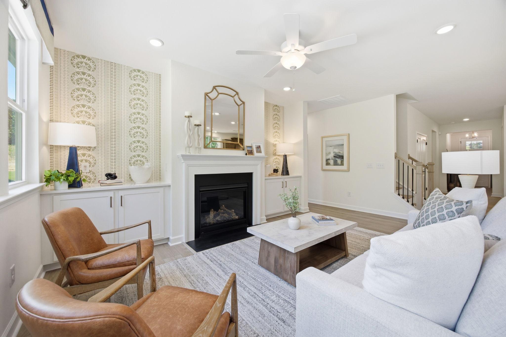 Spacious living room with gas fireplace, leather armchairs, white sofa, and hardwood floors at Sage on North Main in Wake Forest NC