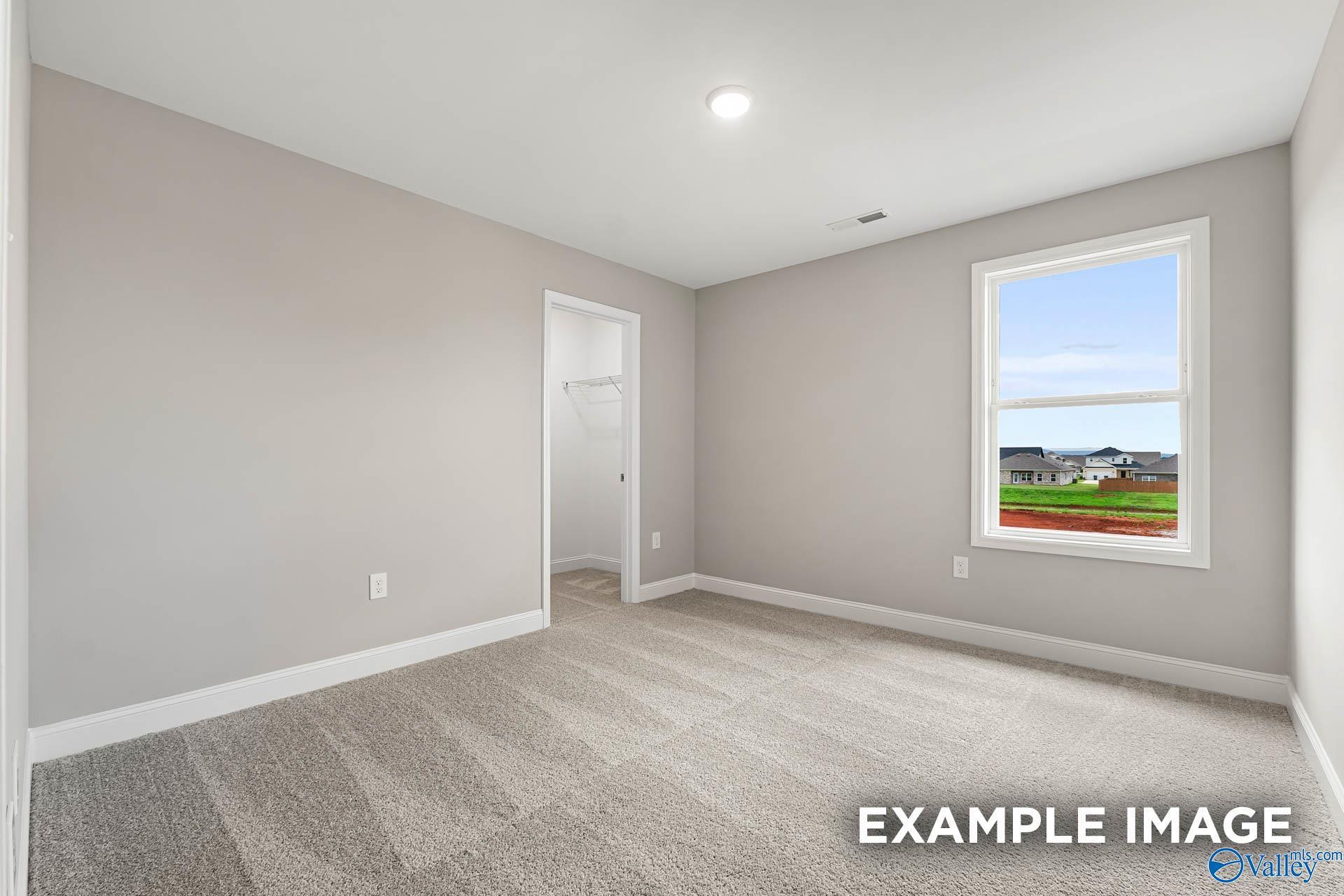 Bright secondary bedroom with gray walls, carpet floor, closet, and window overlooking Ivy Hills neighborhood in Toney, Alabama