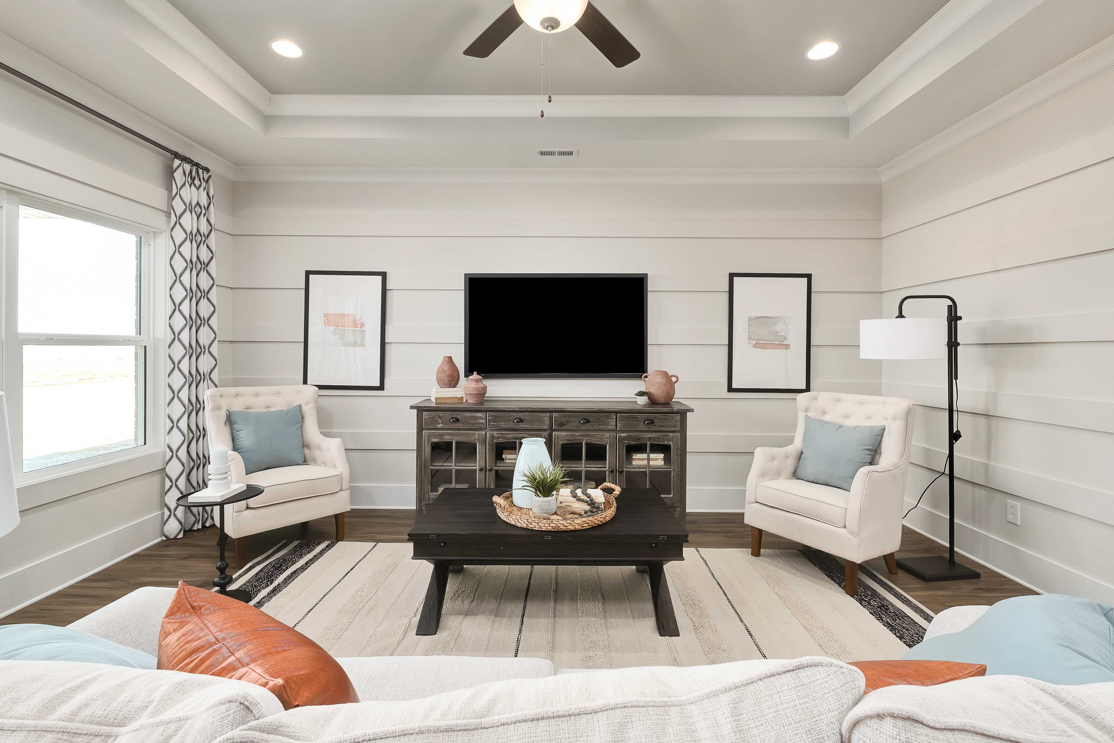 Cozy living room at Mallard Landing in Athens Alabama with shiplap walls, ceiling fan, TV, armchairs, and sectional sofa