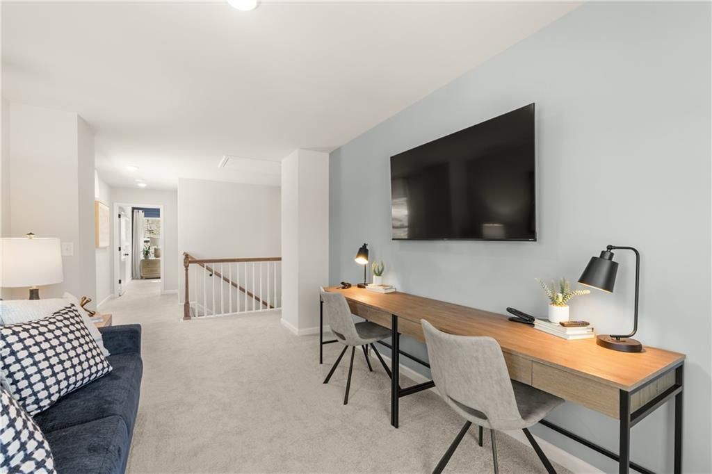 Cozy loft bonus room with wooden desk, mounted TV, blue sofa and lamps in The Burton C floor plan, Davidson Homes, Canton, GA