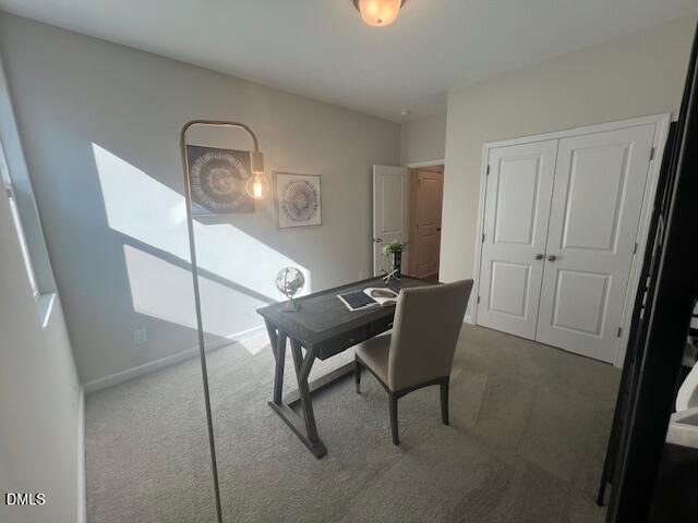 Modern home office with wooden X-leg desk, beige armchair, abstract wall art, and white double doors in Davidson Homes The Preston A, Lillington NC