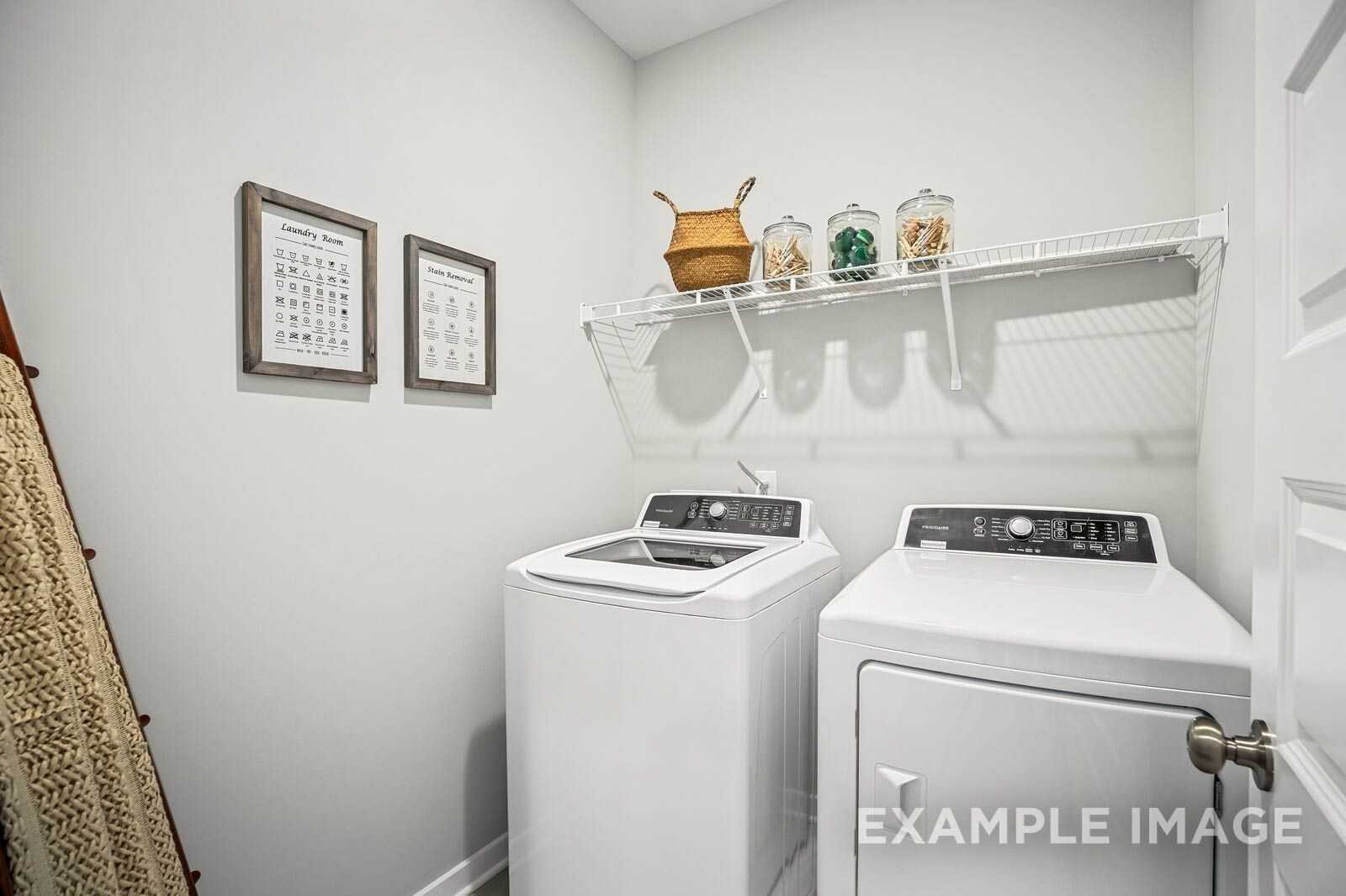 Functional laundry room featuring white washer, dryer, wire shelves with baskets and jars in Davidson Homes The Franklin B, White House, TN