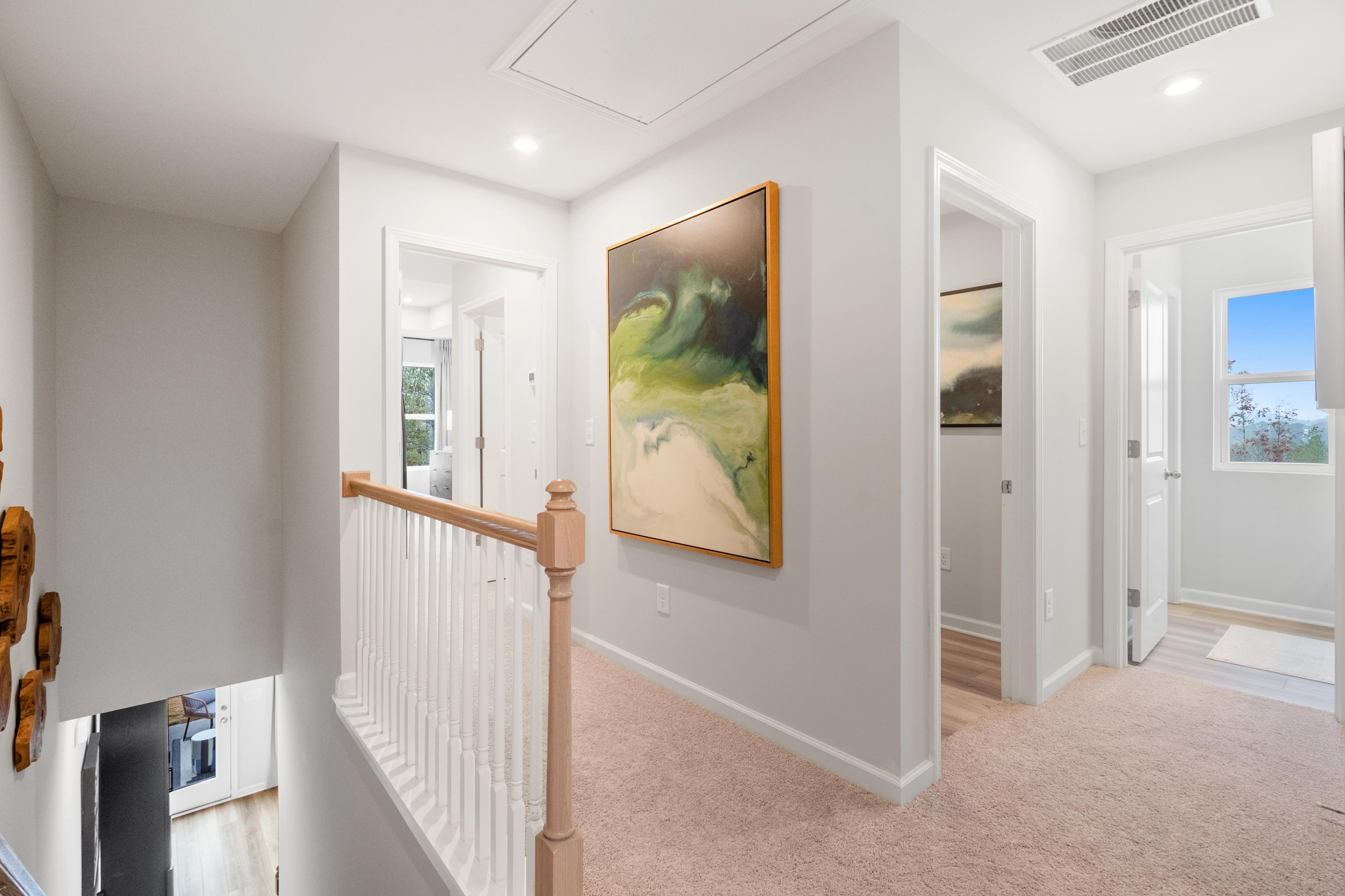 Bright upstairs hallway in Stegall Village Emerson GA home with abstract wall art, white balustrade, and carpeted floors